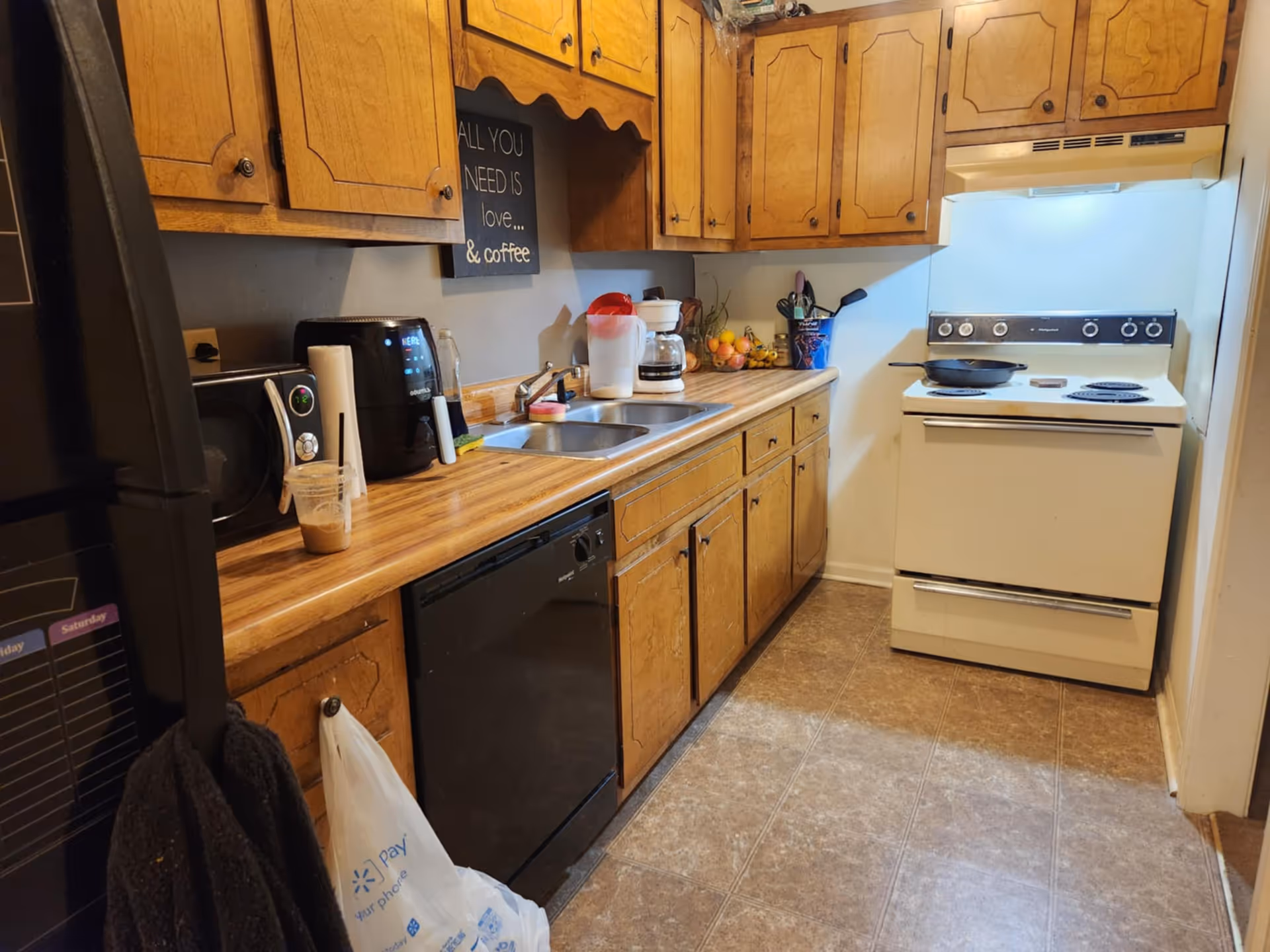 Compact kitchen with wooden cabinets, stove, sink, and appliances in FirstLight Home Care of Clarksville.