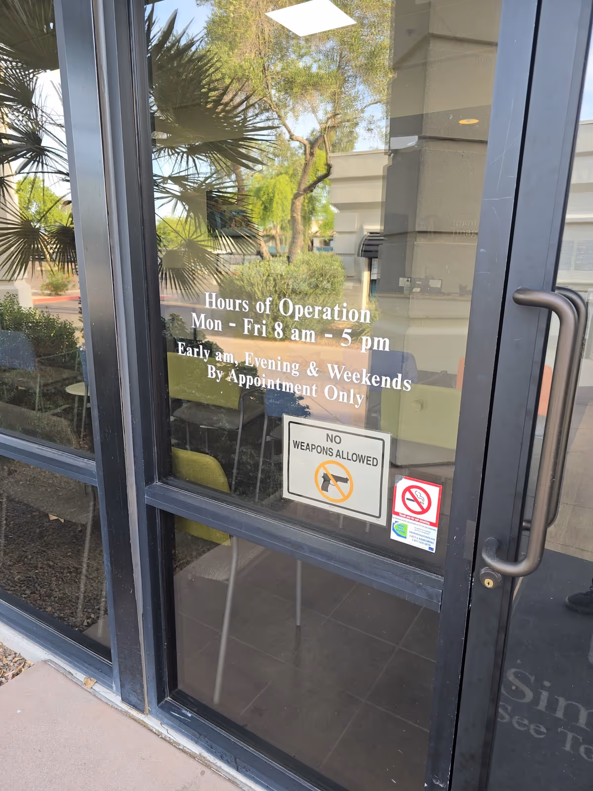 Glass entrance door with hours of operation signs and notices for Simon Med facility.