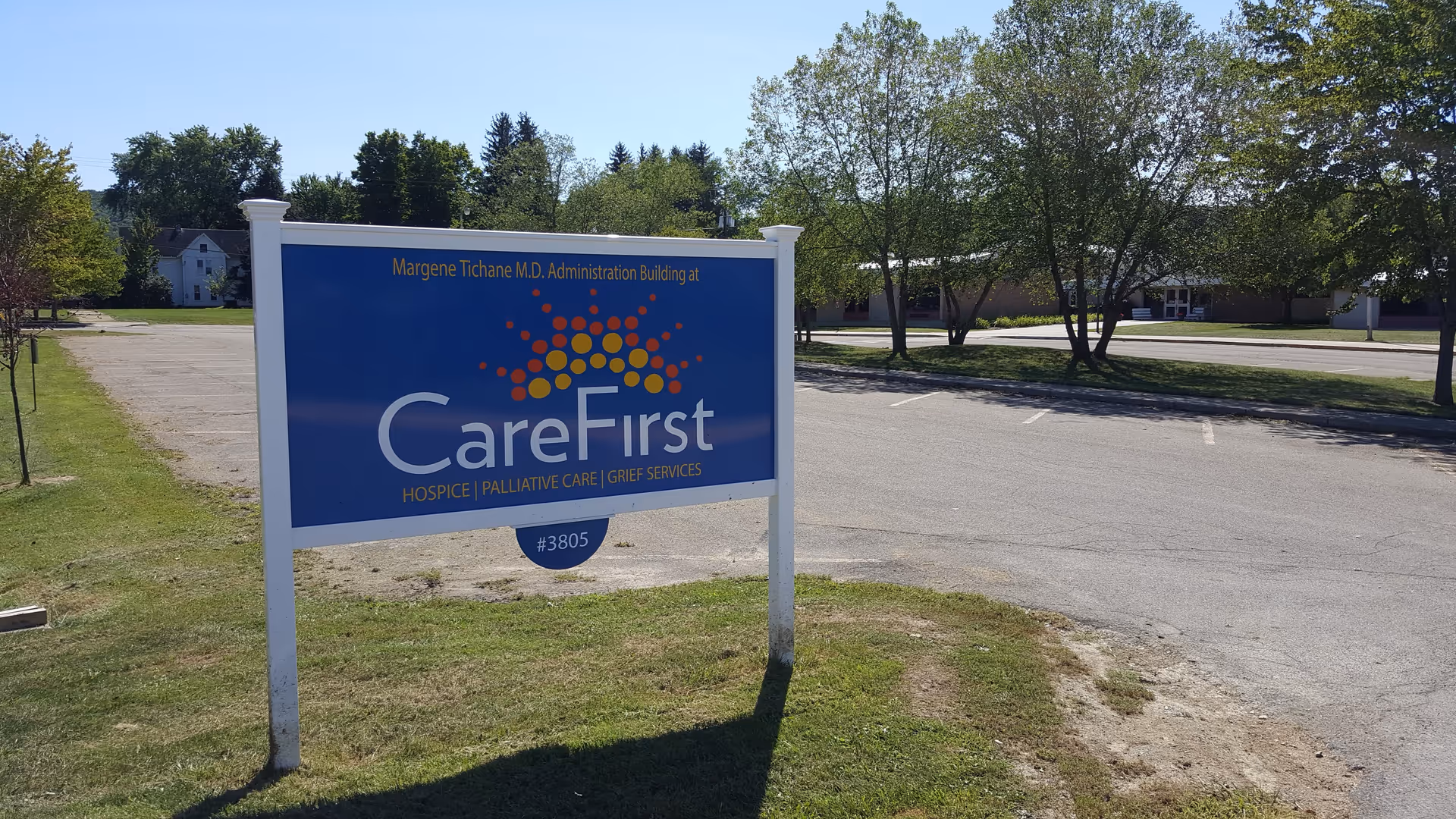 A blue CareFirst sign on a grassy lot with trees and a road beyond.
