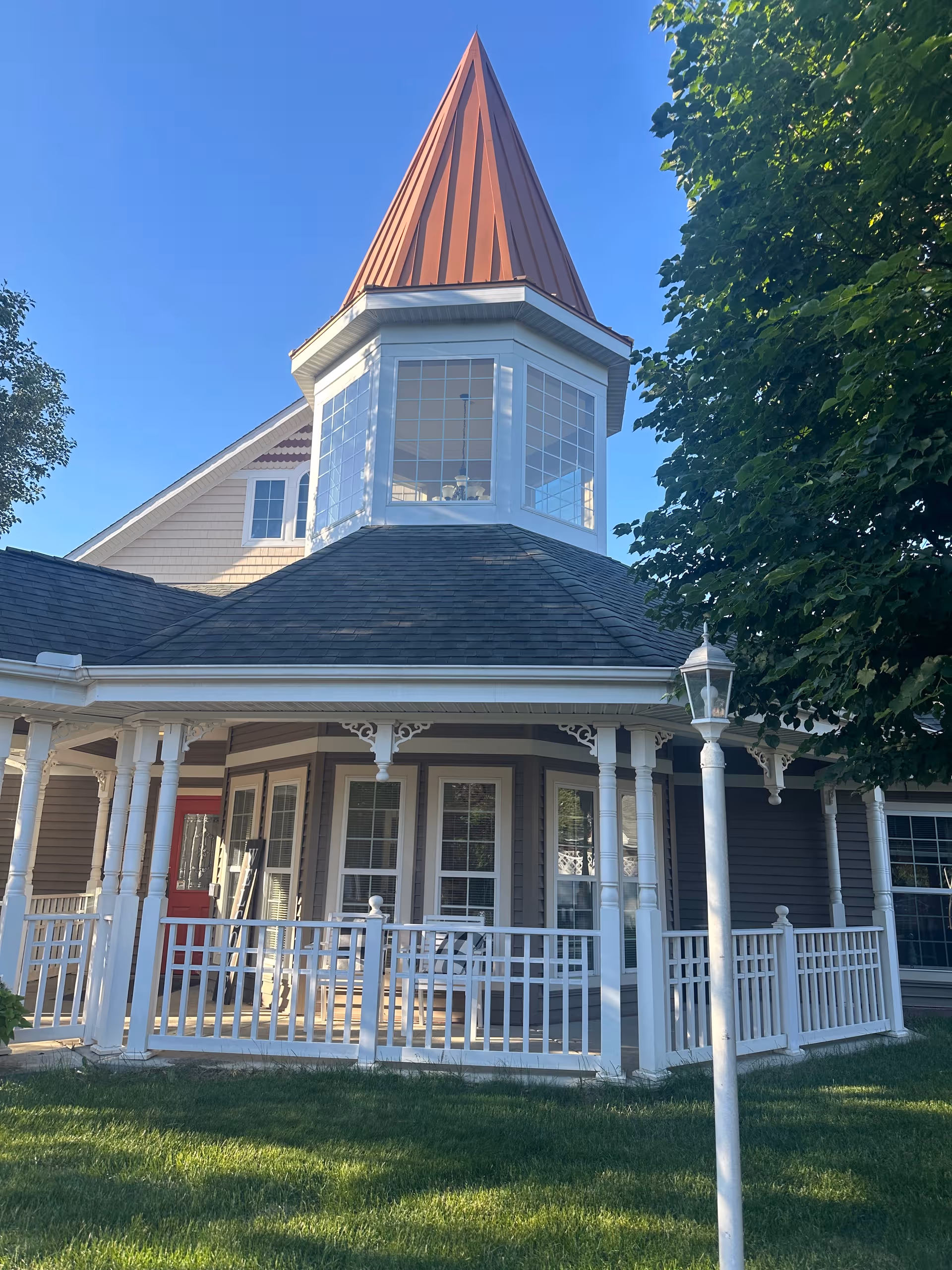 Exterior view of Symphony Linden facility with a wraparound porch, white railings, and a copper turret.