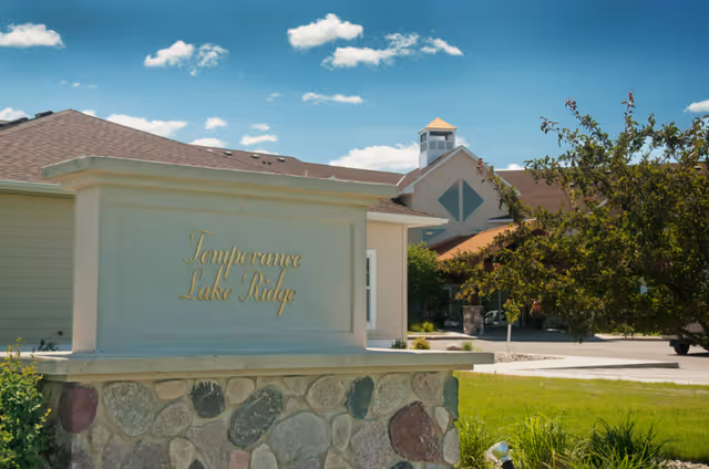 Exterior view of Temperance Lake Ridge Senior Living entrance sign with building nearby