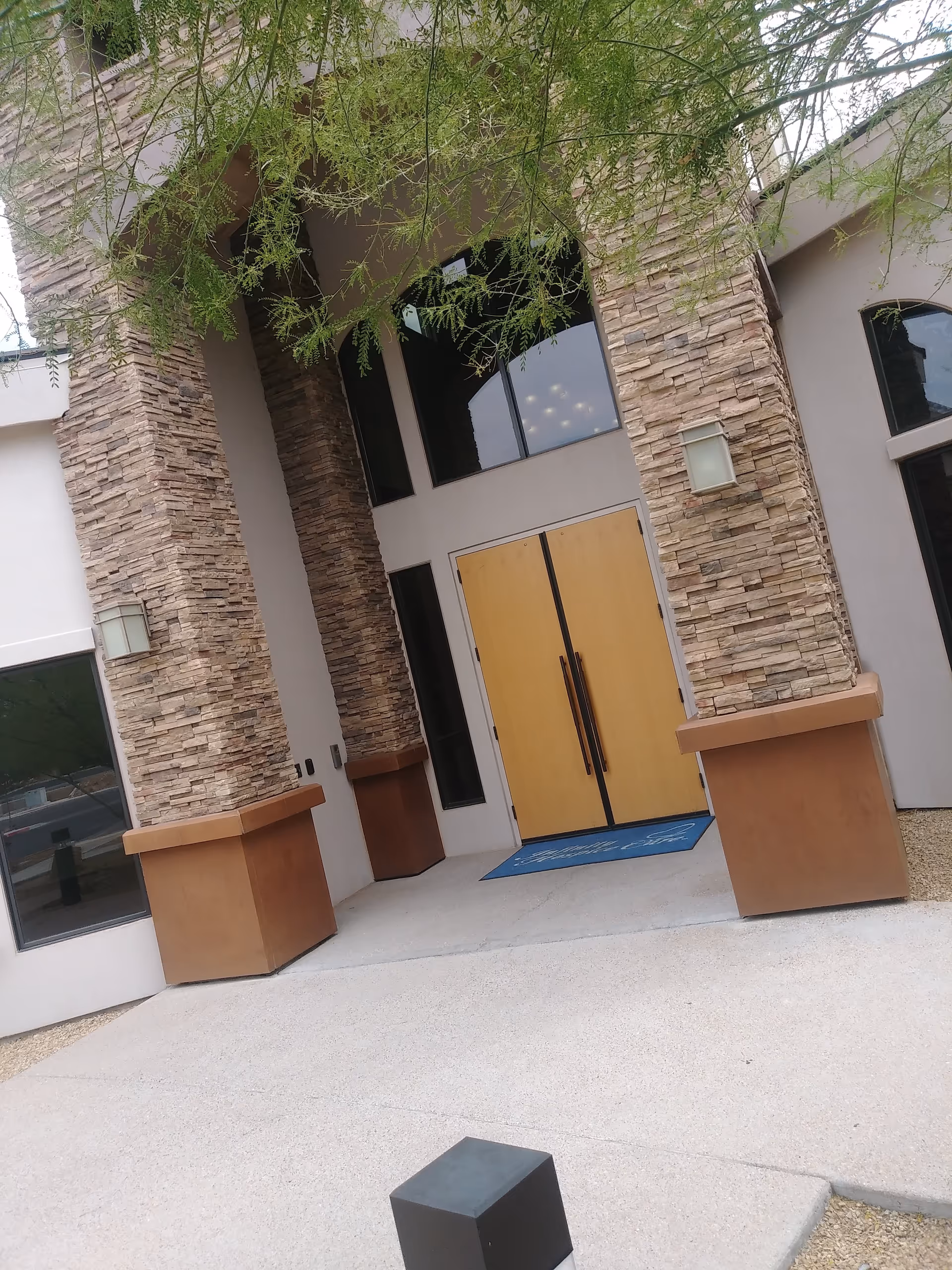 Front entrance of Infinity Hospice Care building with stone columns and wooden doors.