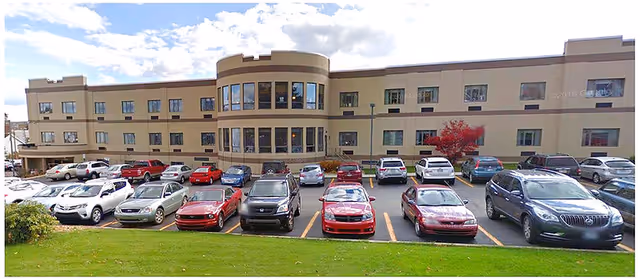 Exterior view of Patriot Village Nursing and Rehab building with a front parking lot