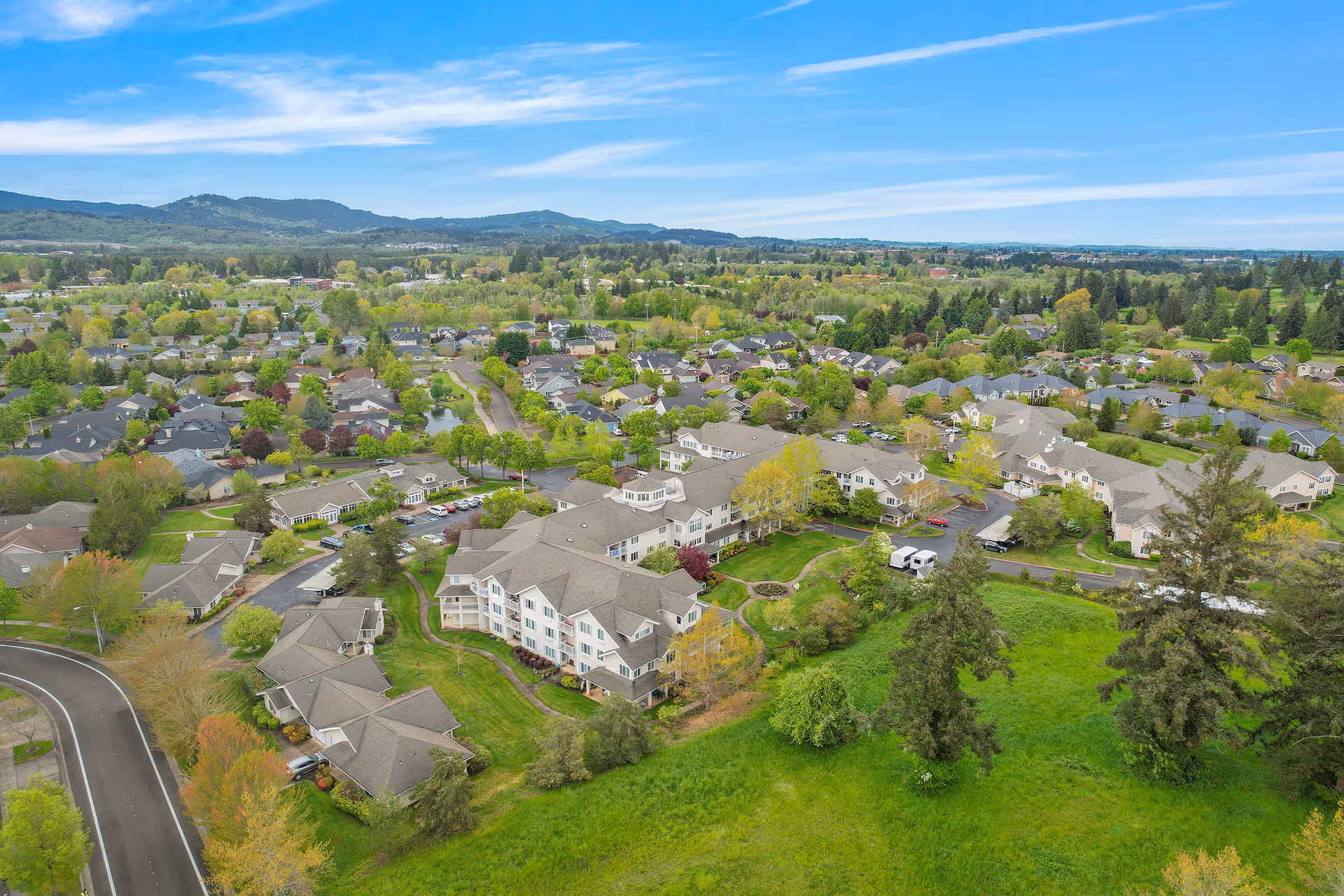 Aerial view of a green suburban retirement community with beige townhomes and trees.