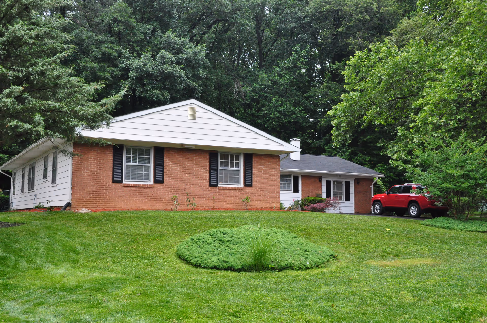 Exterior view of a brick and white assisted living facility with a manicured lawn.