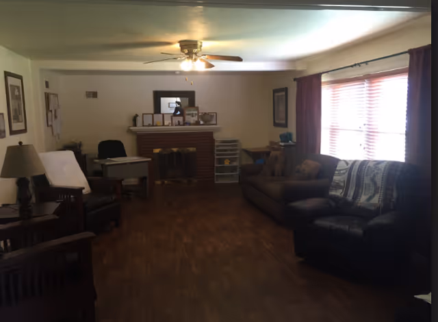 Cozy living room with brick fireplace, sofas, chairs, and a large window.