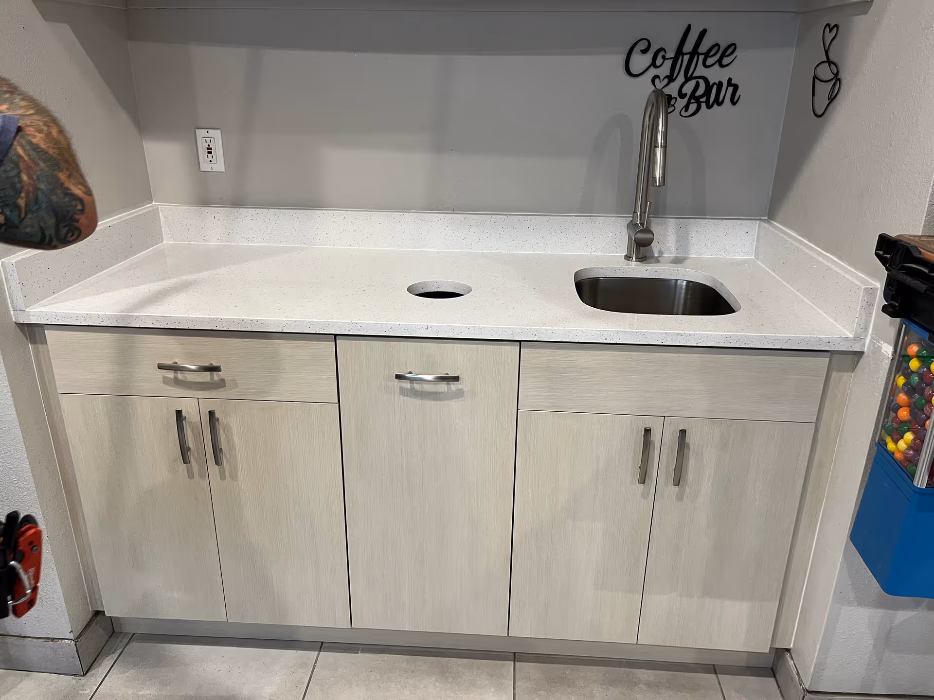 Small, clean kitchenette with sink, cabinets, and a coffee bar sign.