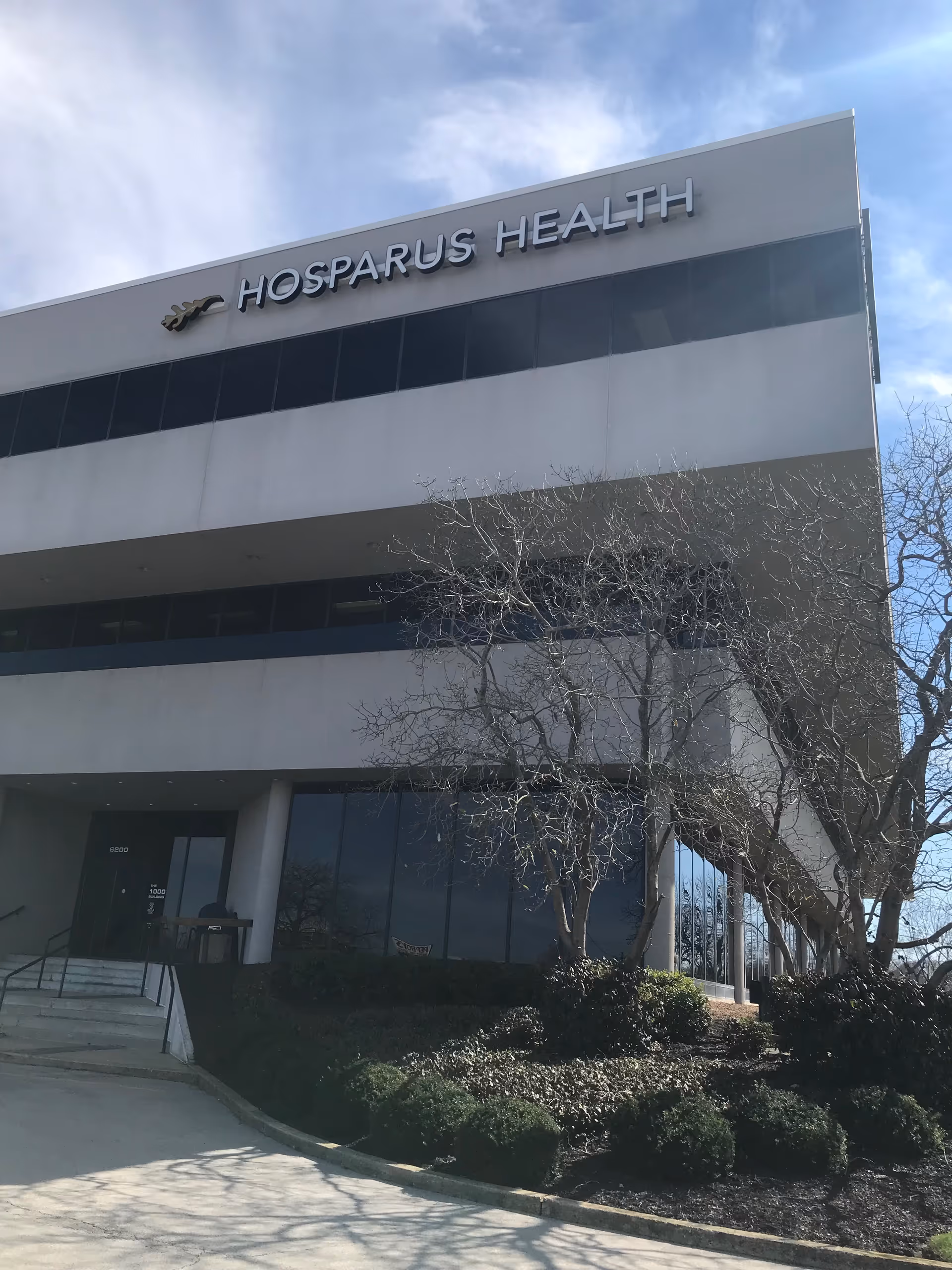 Exterior view of a Hosparus Health building with glass windows and landscaping.
