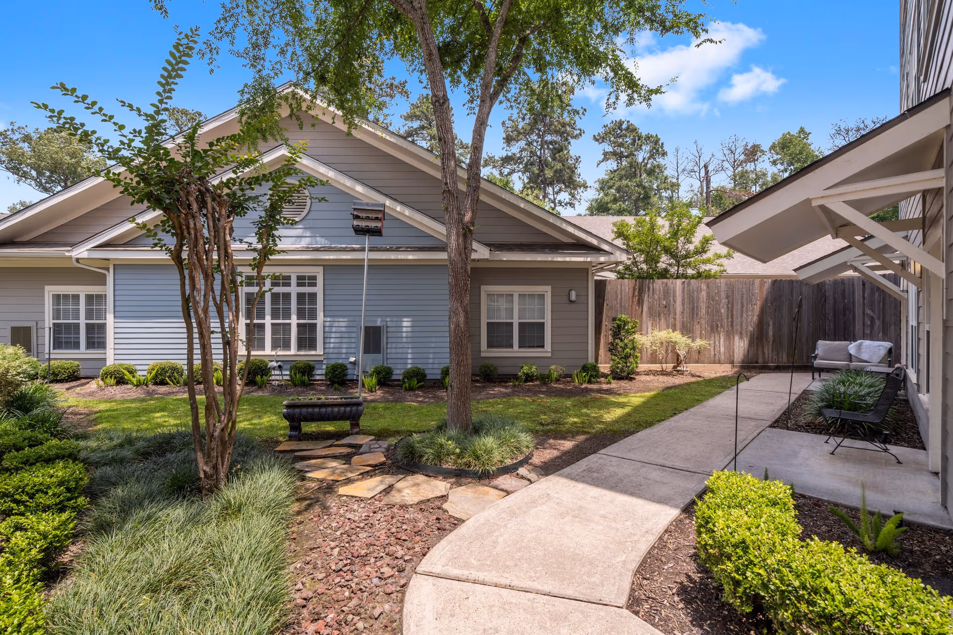 Exterior of Sundale Senior Living of the Woodlands, with landscaped courtyard and outdoor seating.