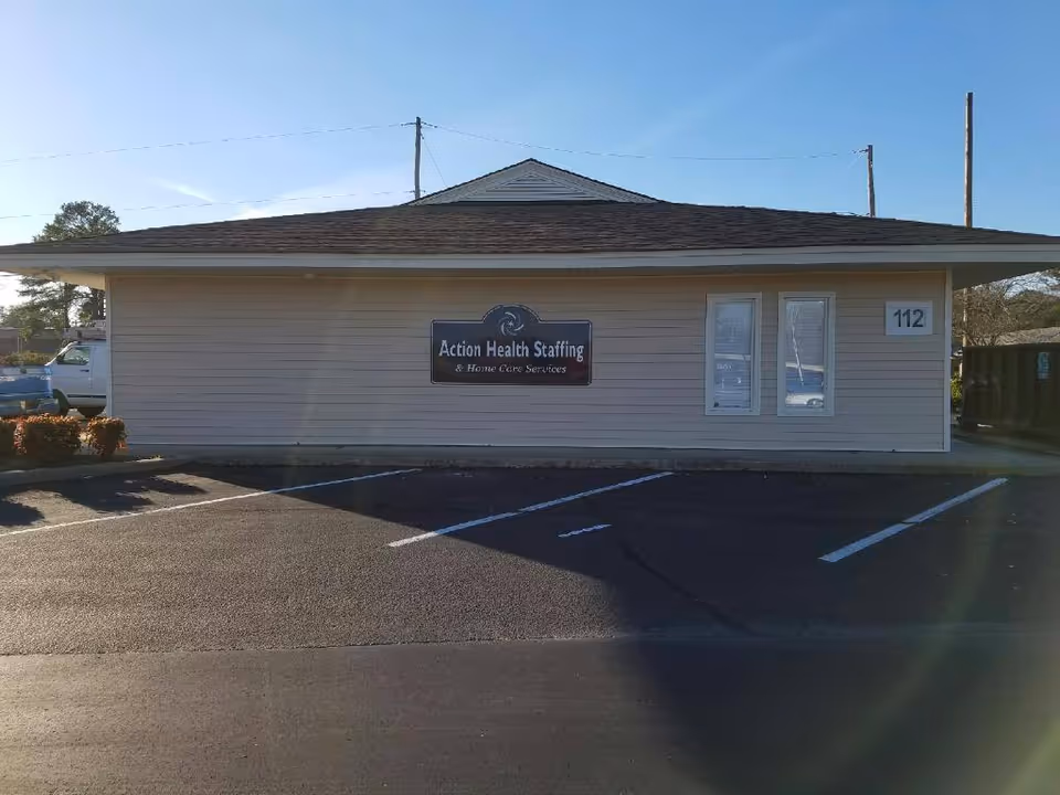 Single-story beige building with Action Health Staffing sign and a parking lot in front.