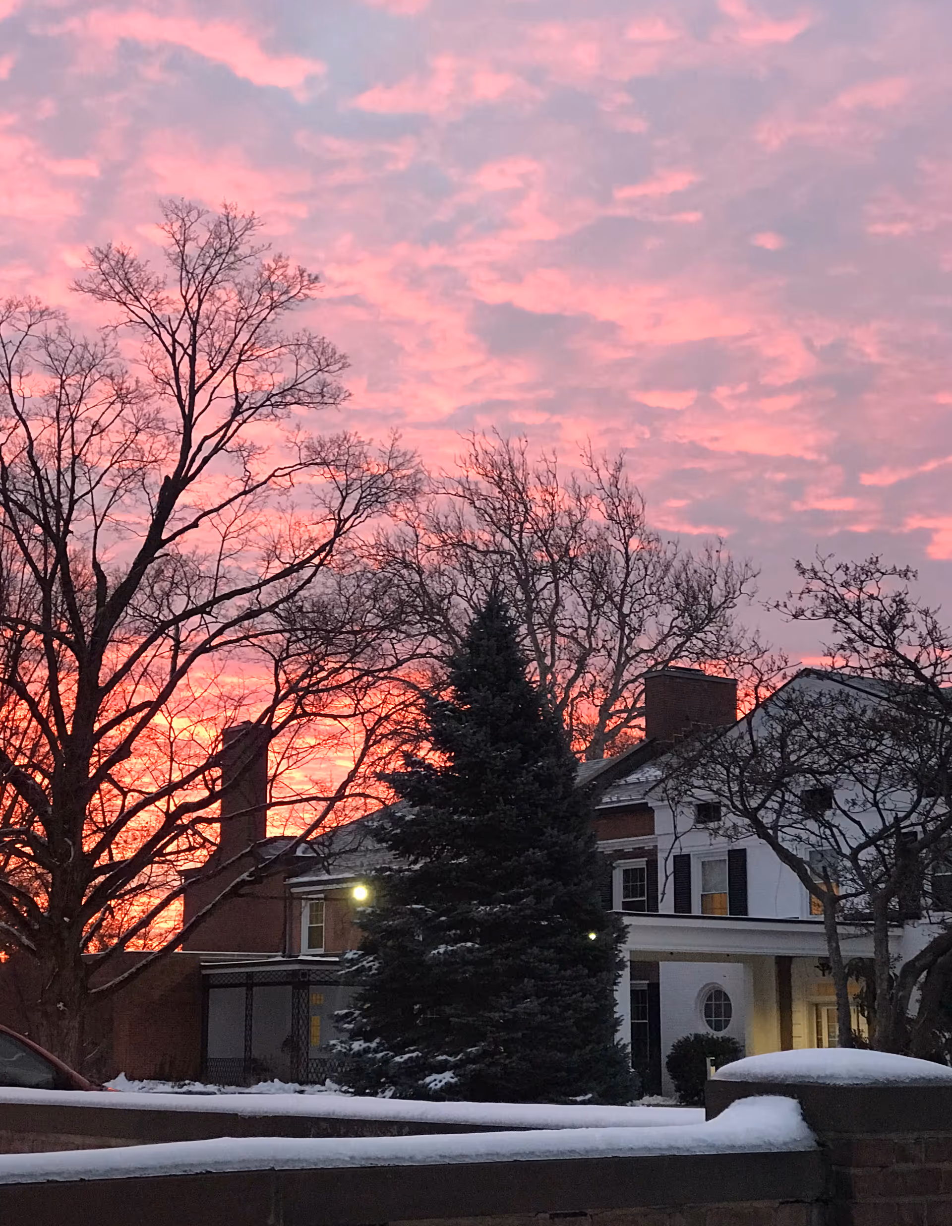 Exterior view of Bradley Home and Pavilion with snow, trees, and pink sunset sky.