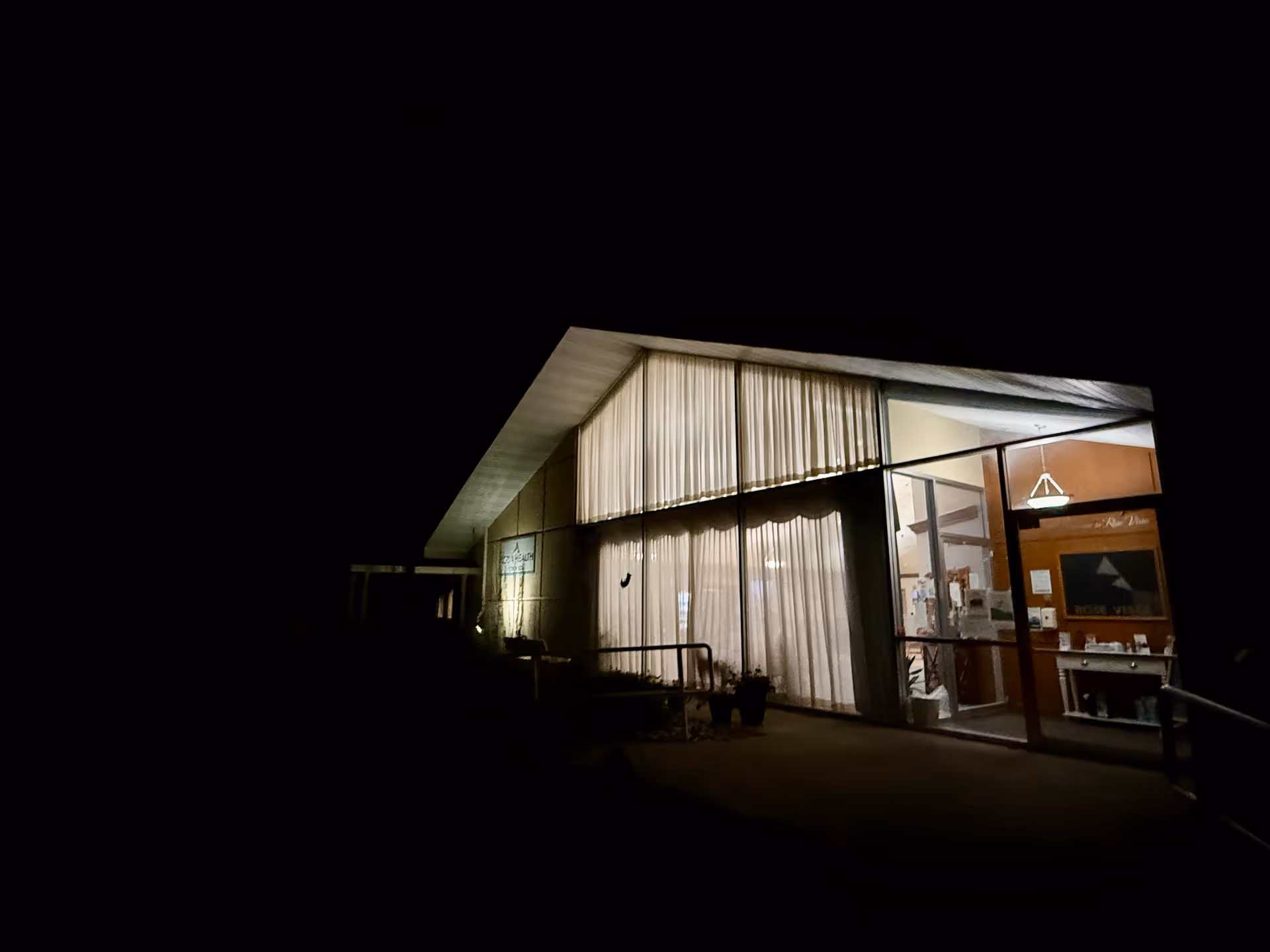 Azria Health Rose Vista facility exterior at night with illuminated glass entrance.