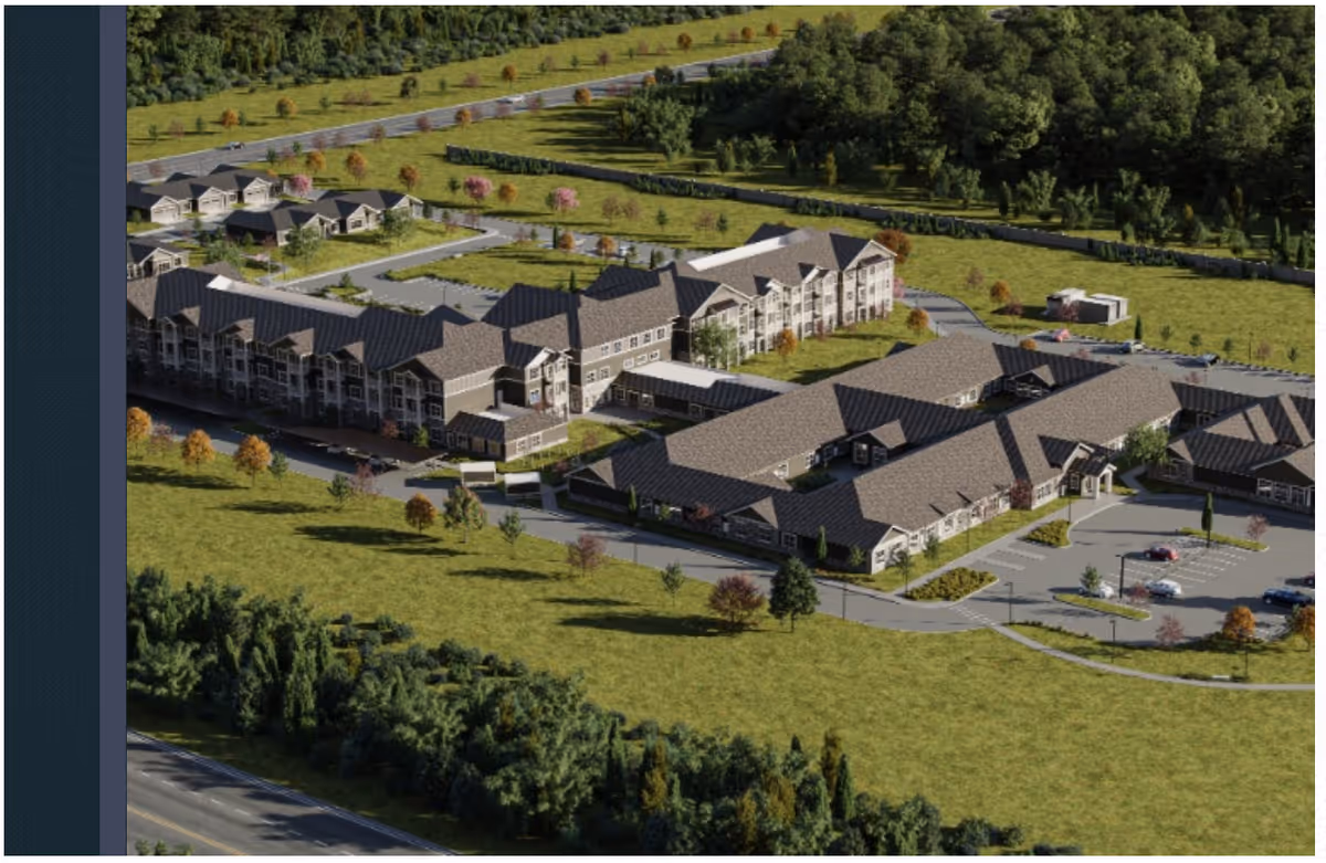 Aerial view of a senior living campus with multiple connected residential buildings, parking areas, and surrounding lawns and trees.