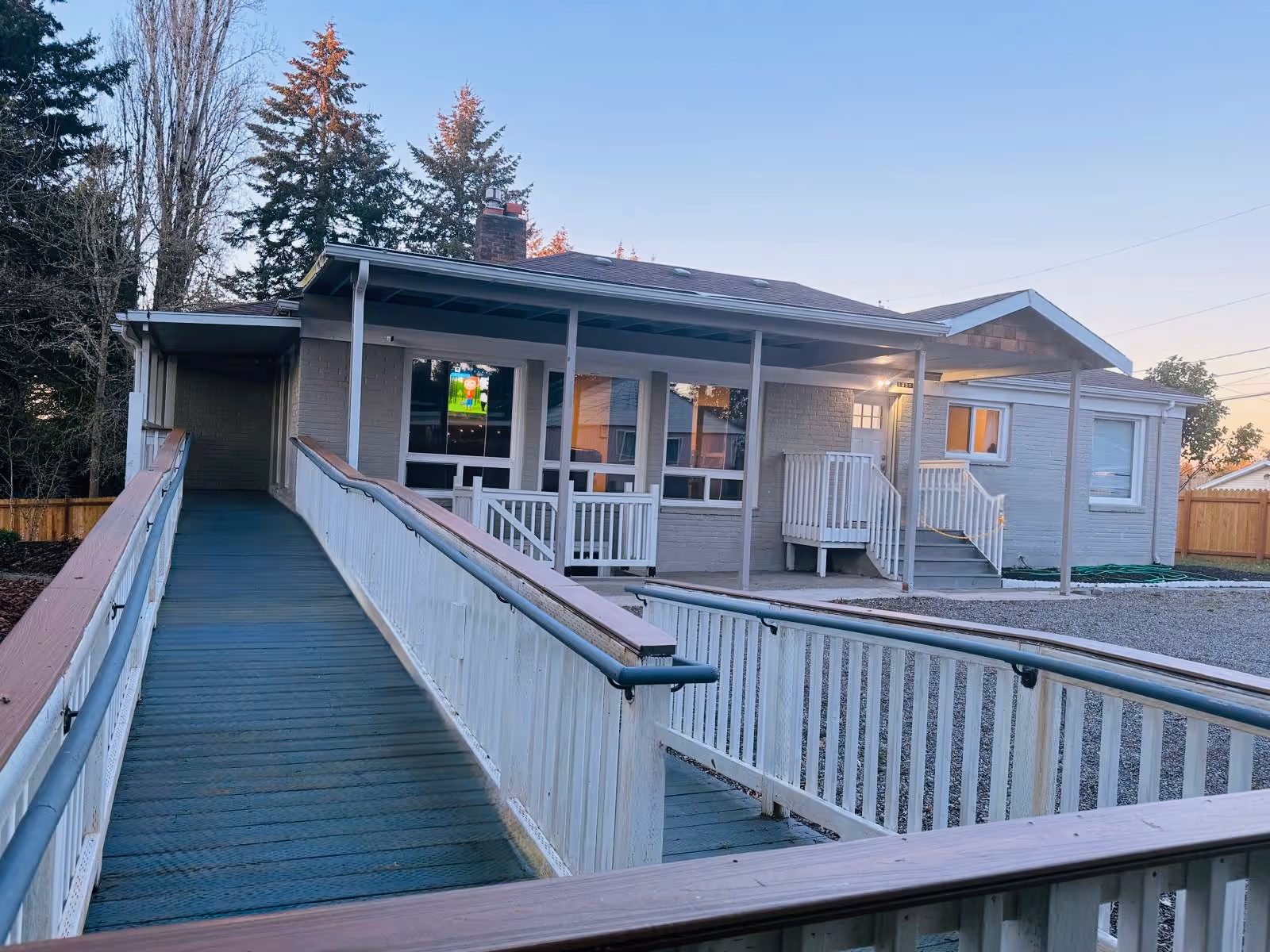 Exterior view of a single-story senior living facility with a wheelchair ramp and porch.
