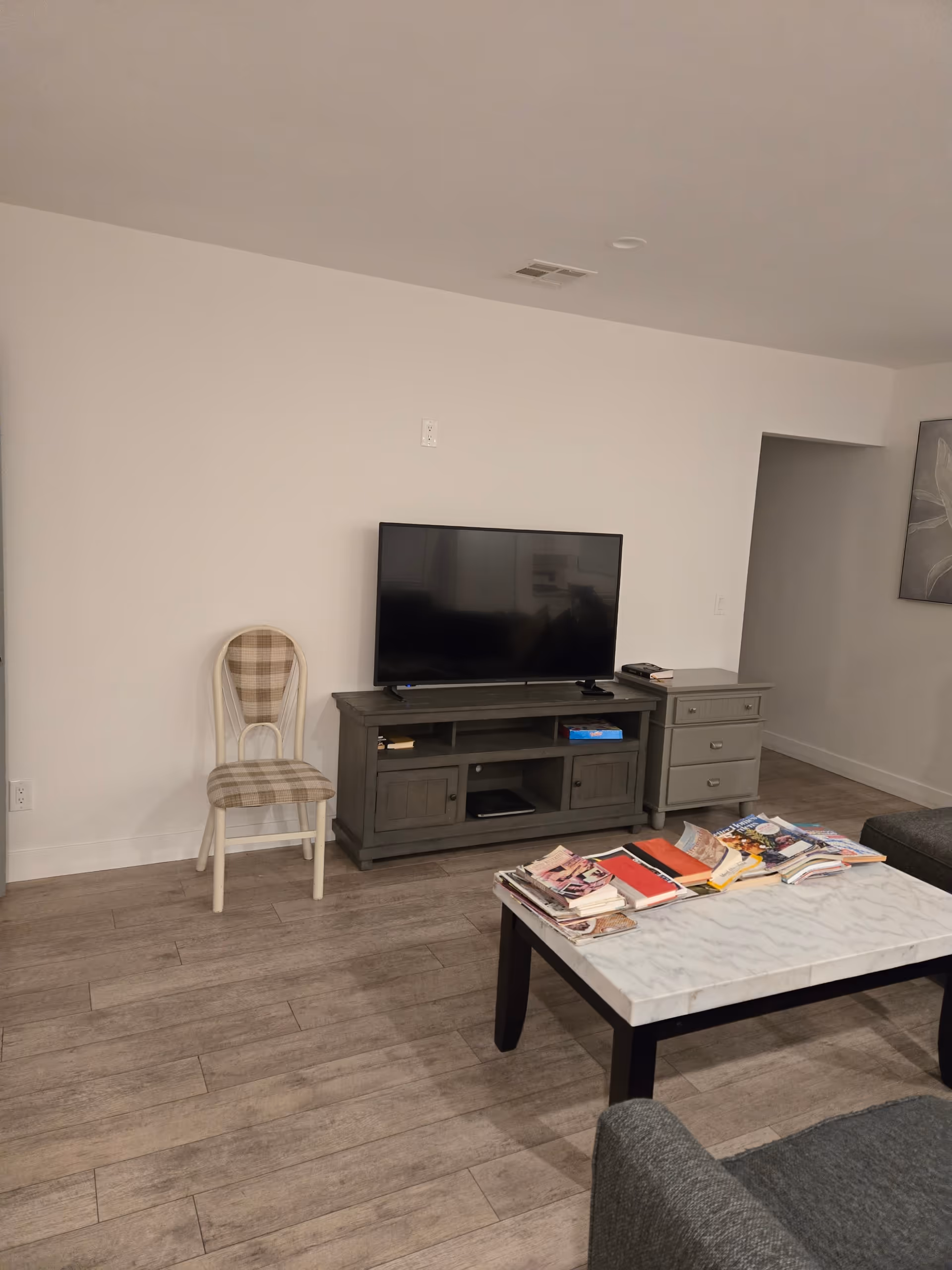 Cozy living room with TV stand, chair, coffee table, and magazines.