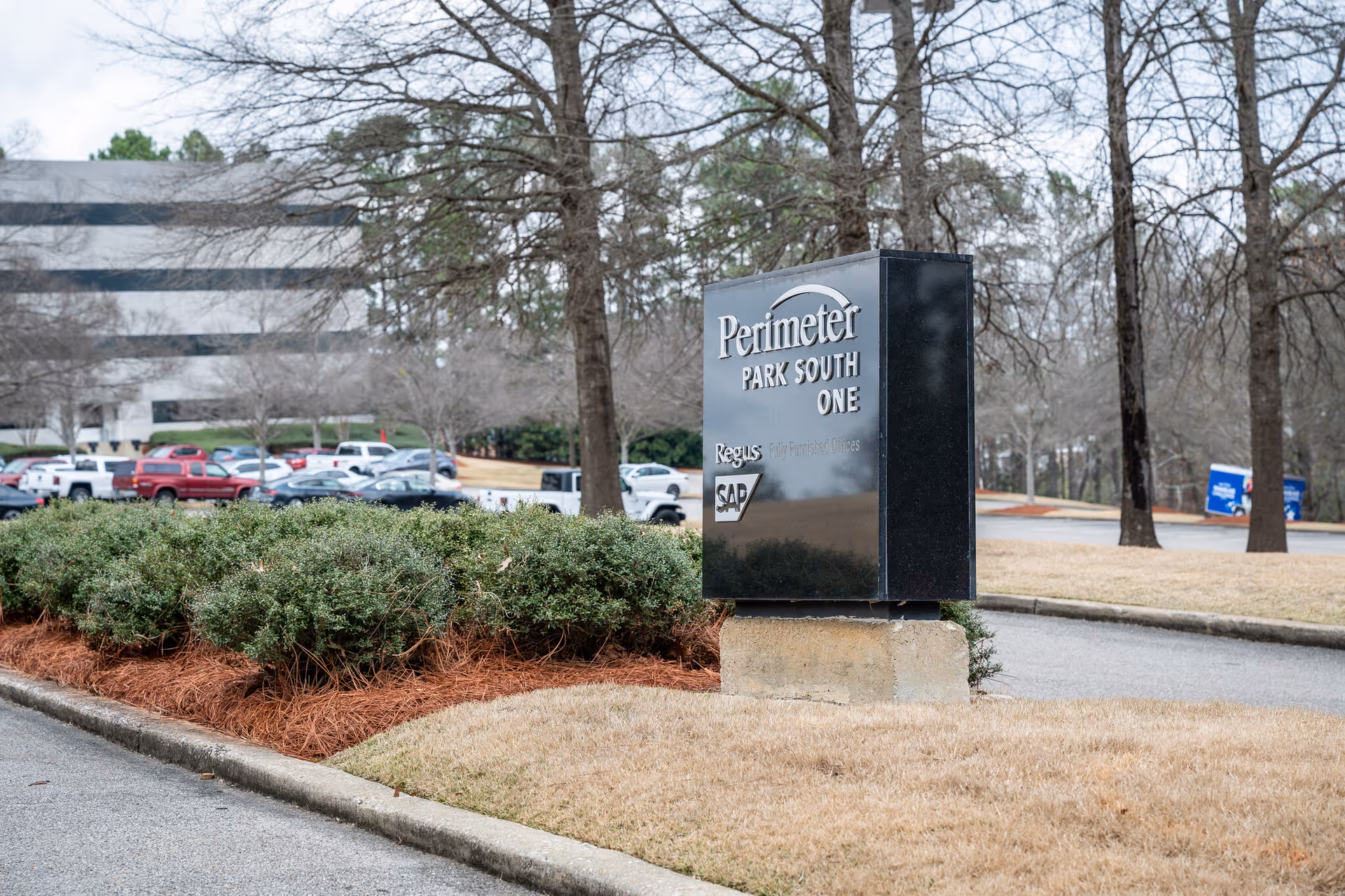 Exterior view of a parking lot with a large black sign reading Perimeter Park South One