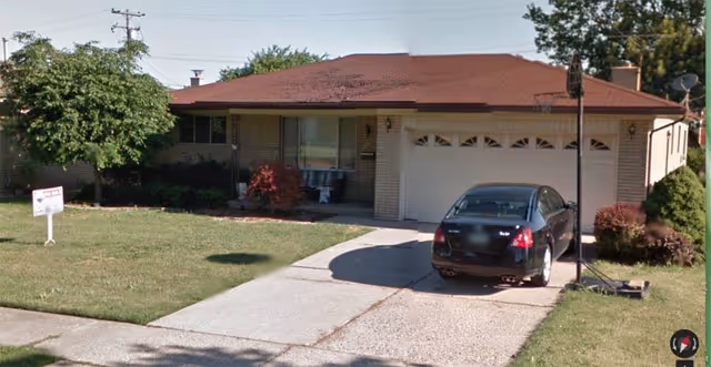 Single-story residence with a driveway, garage, and a black car parked in front.