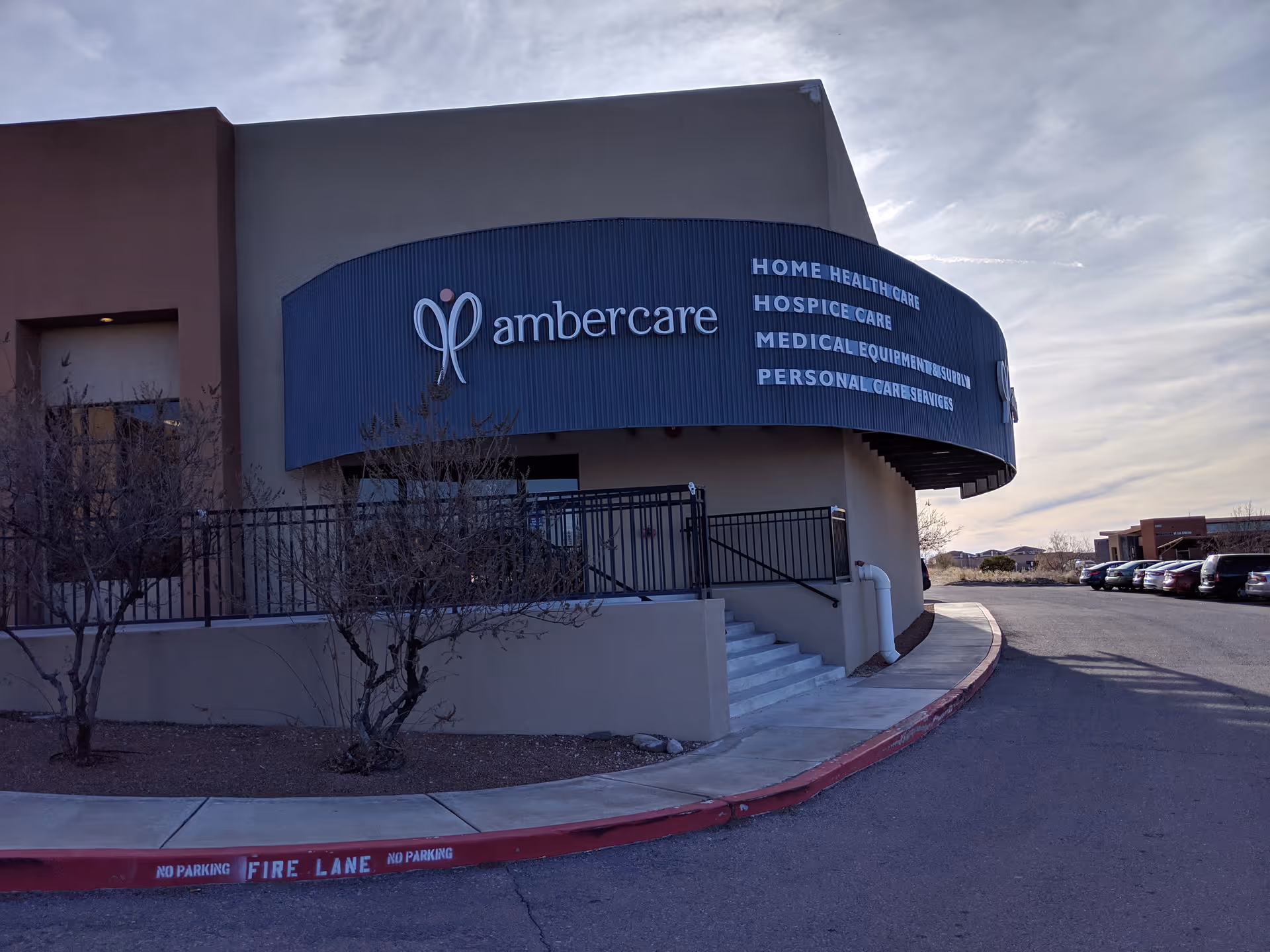 Exterior view of Ambercare building with curved blue sign and parked cars nearby.