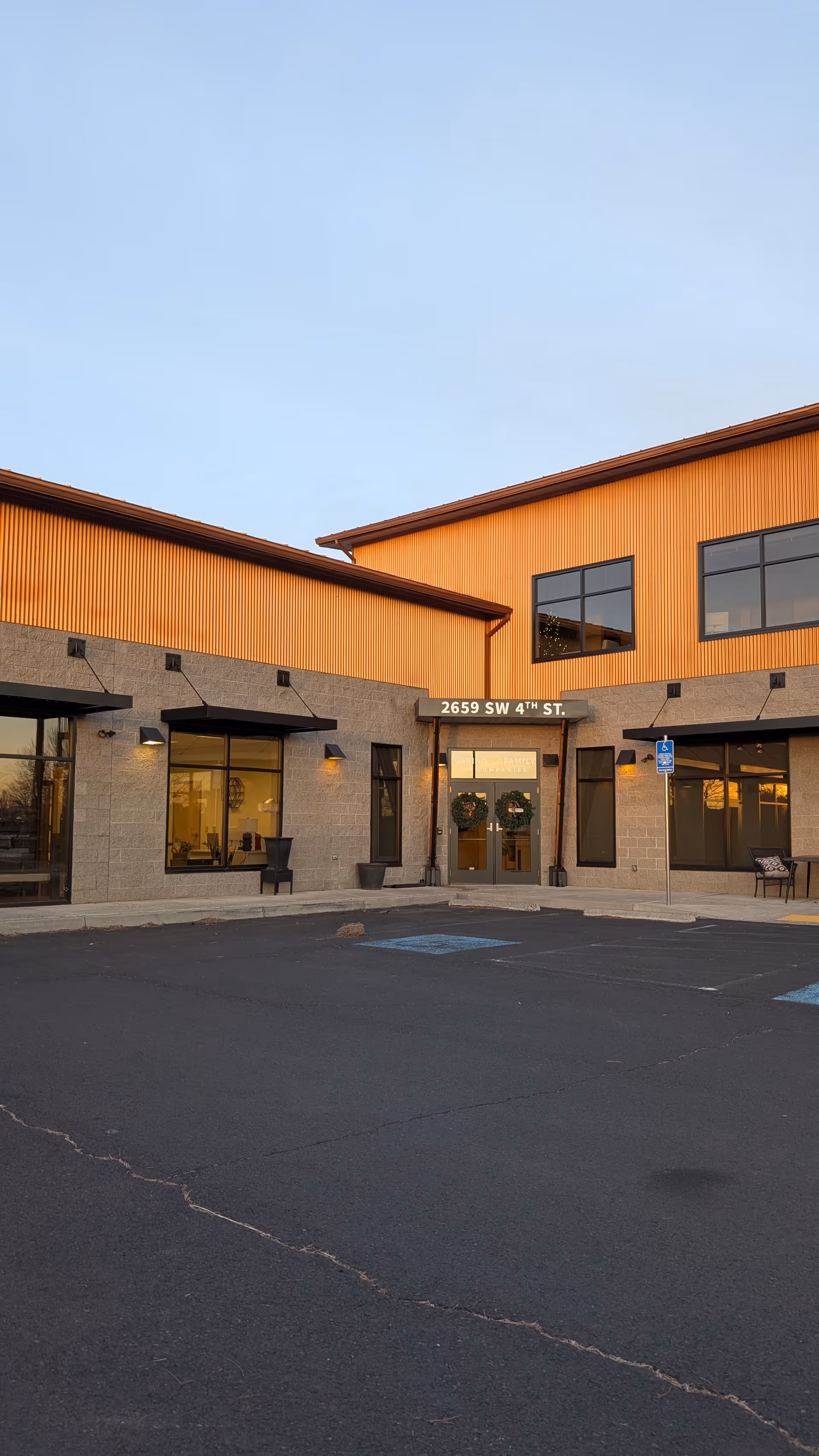 Exterior view of a senior living facility entrance with parking lot and clear sky.