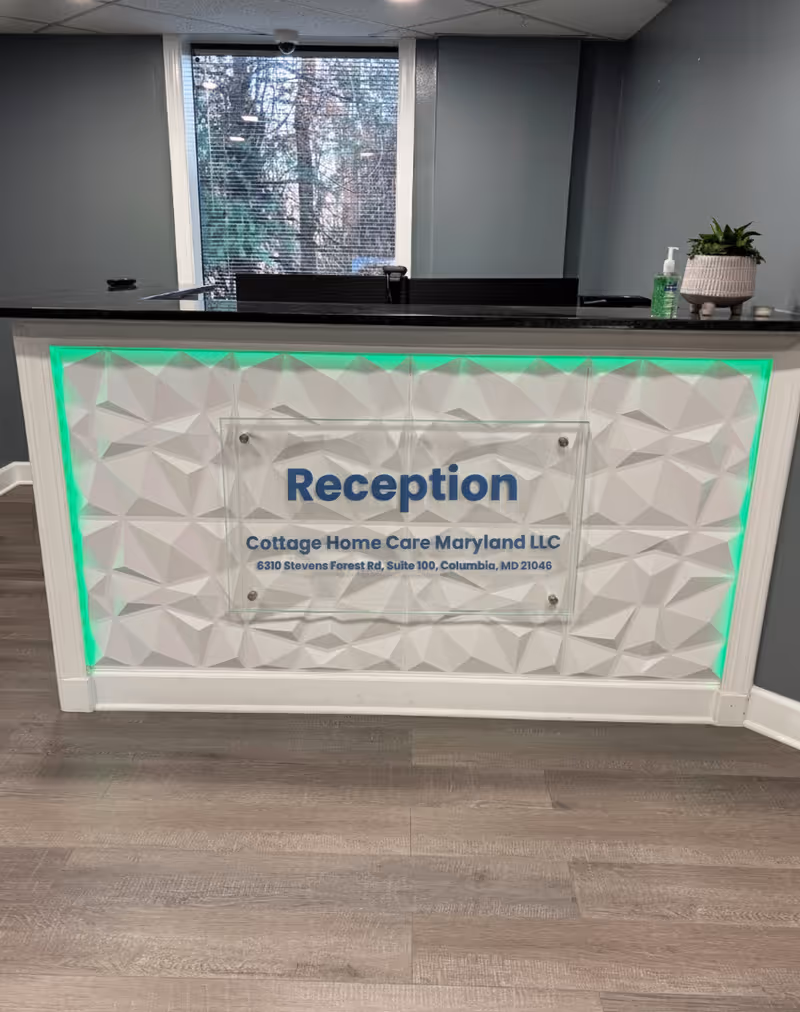 Reception desk inside a modern lobby with green illuminated trim and plant decor.