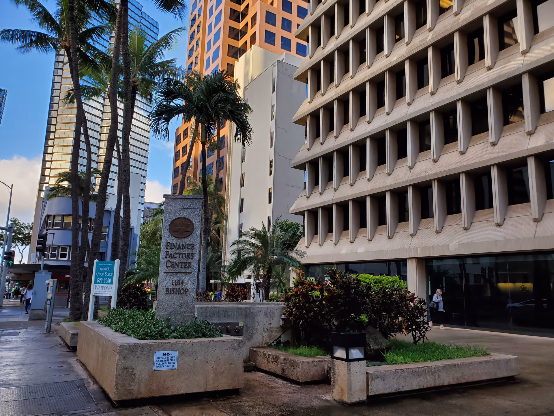 Urban street scene with tall buildings, palm trees, and Finance Factors Center sign.