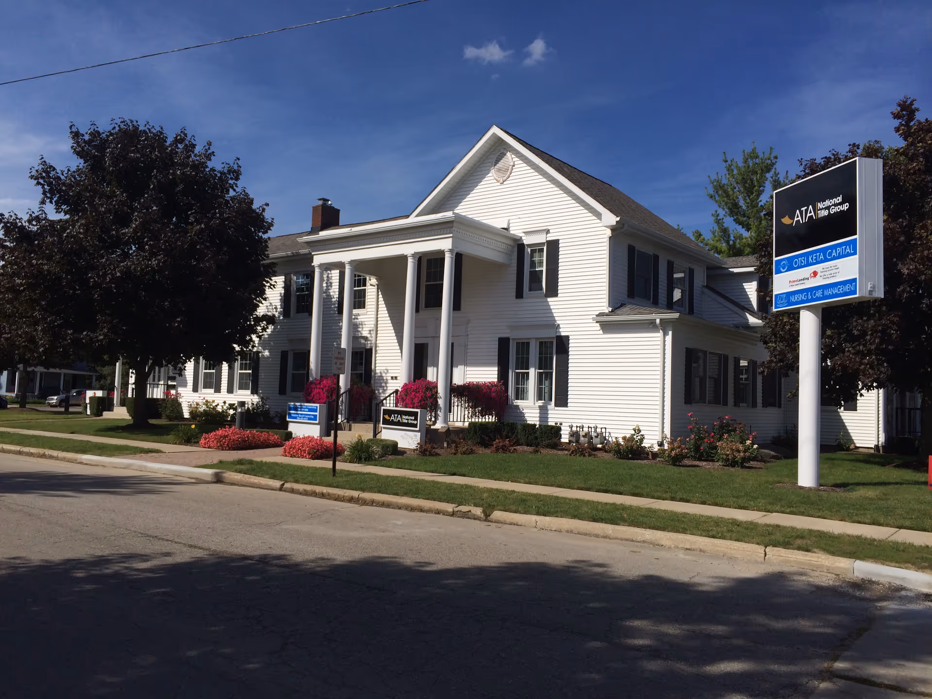 White two-story building with columns and a tall sign in the front yard.