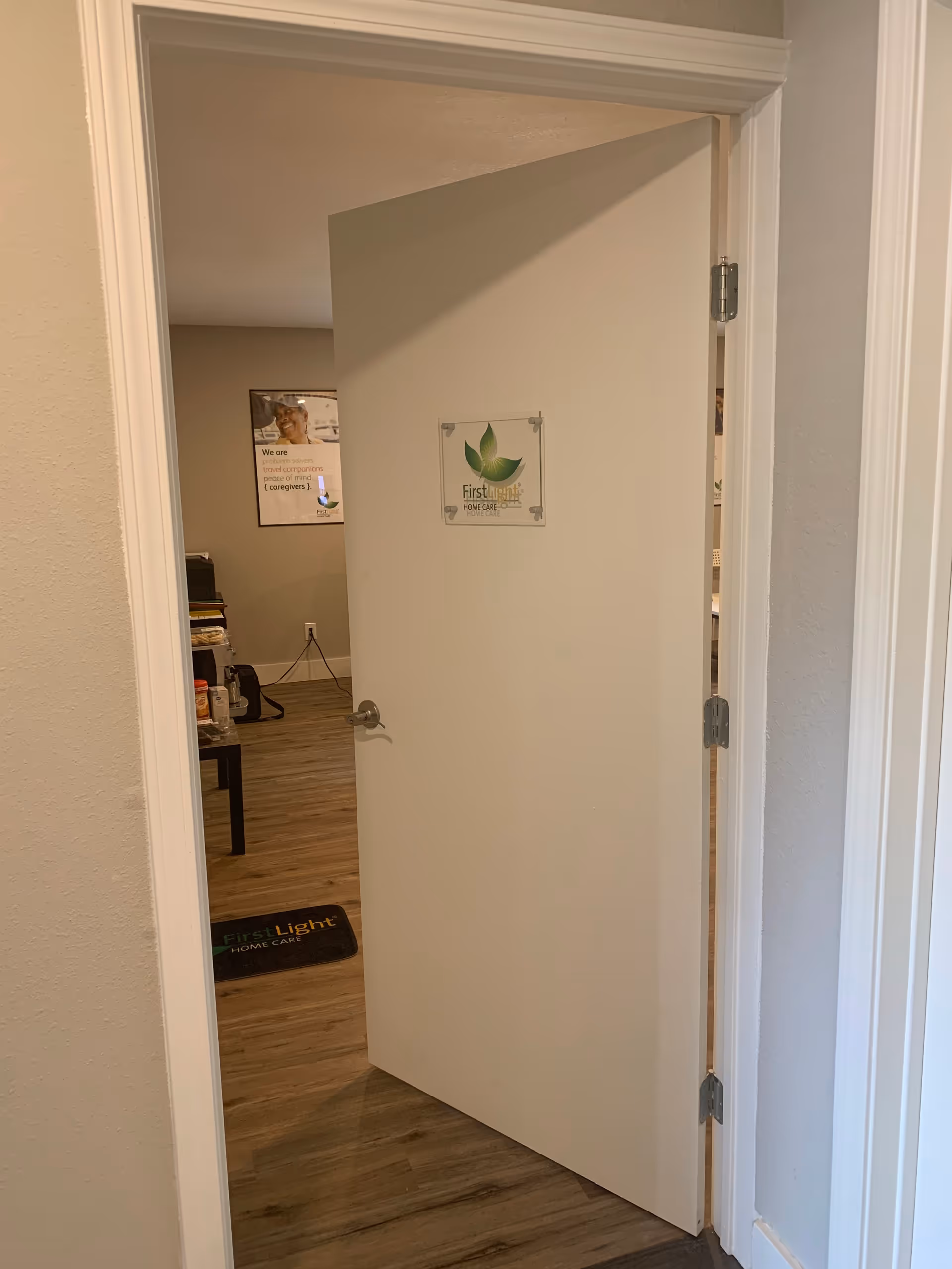 Open door reveals a FirstLight Home Care sign inside a small office area.