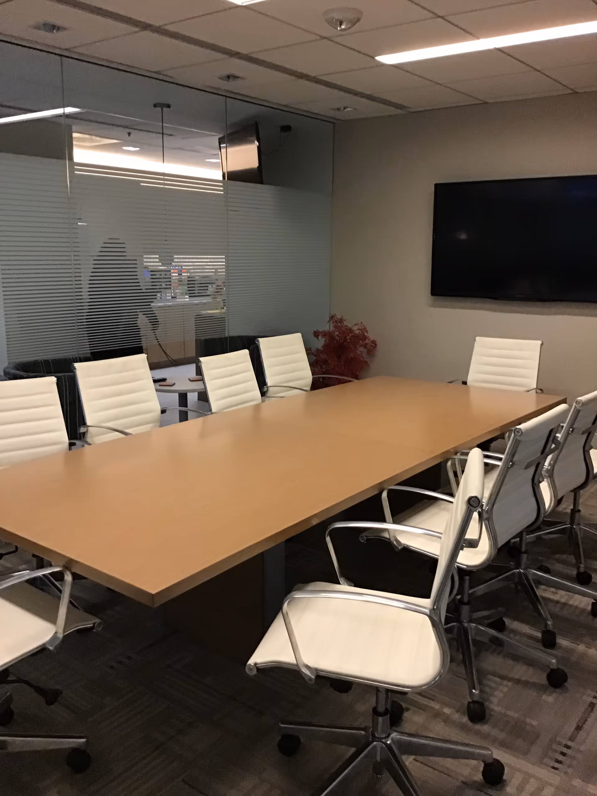 A conference room with a wooden table and white swivel chairs in a senior living facility.