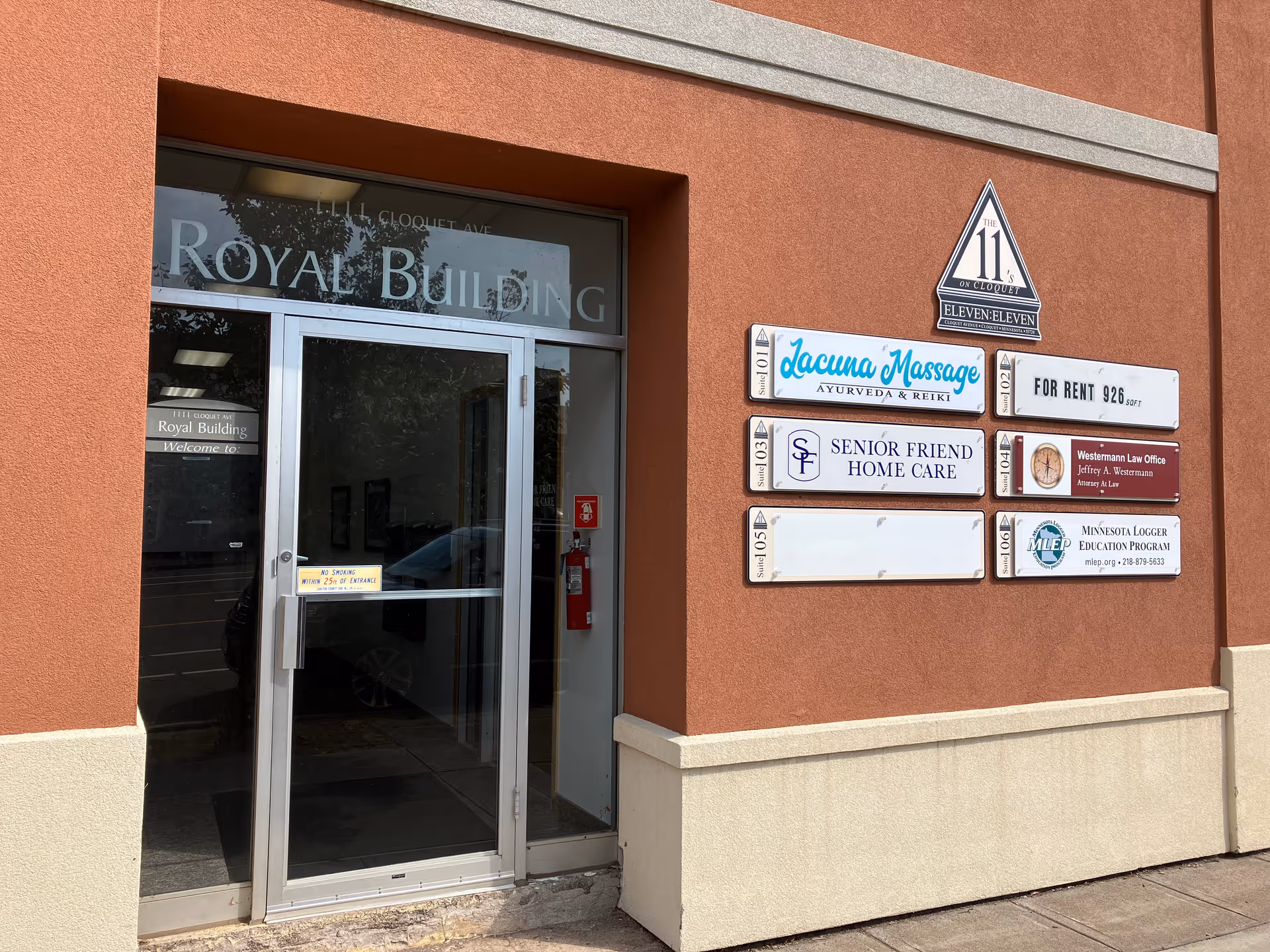 Exterior of building with glass entrance and sign plaques, including Senior Friend Home Care.