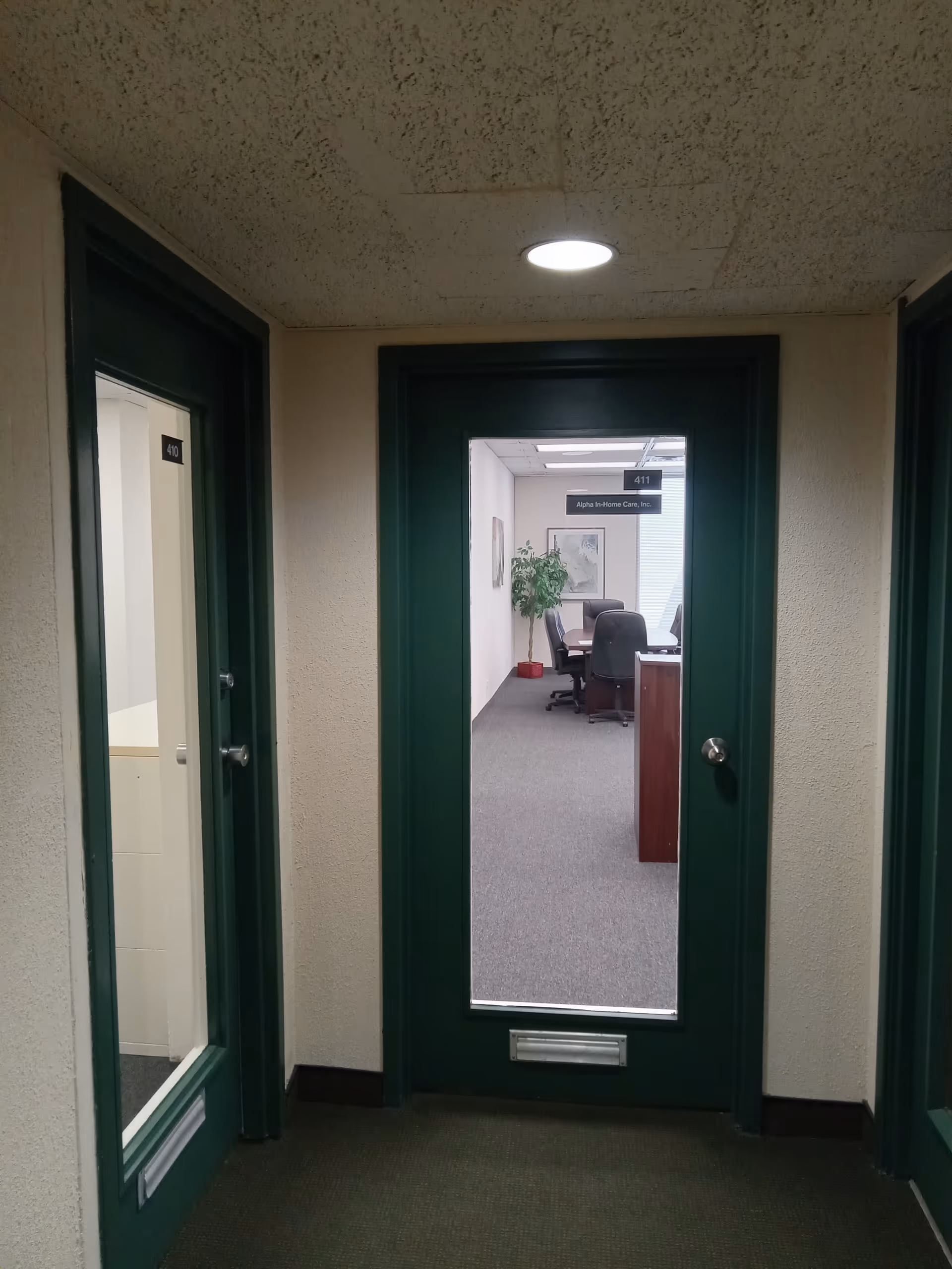 Interior hallway with green doors leading to office rooms in a senior living facility.