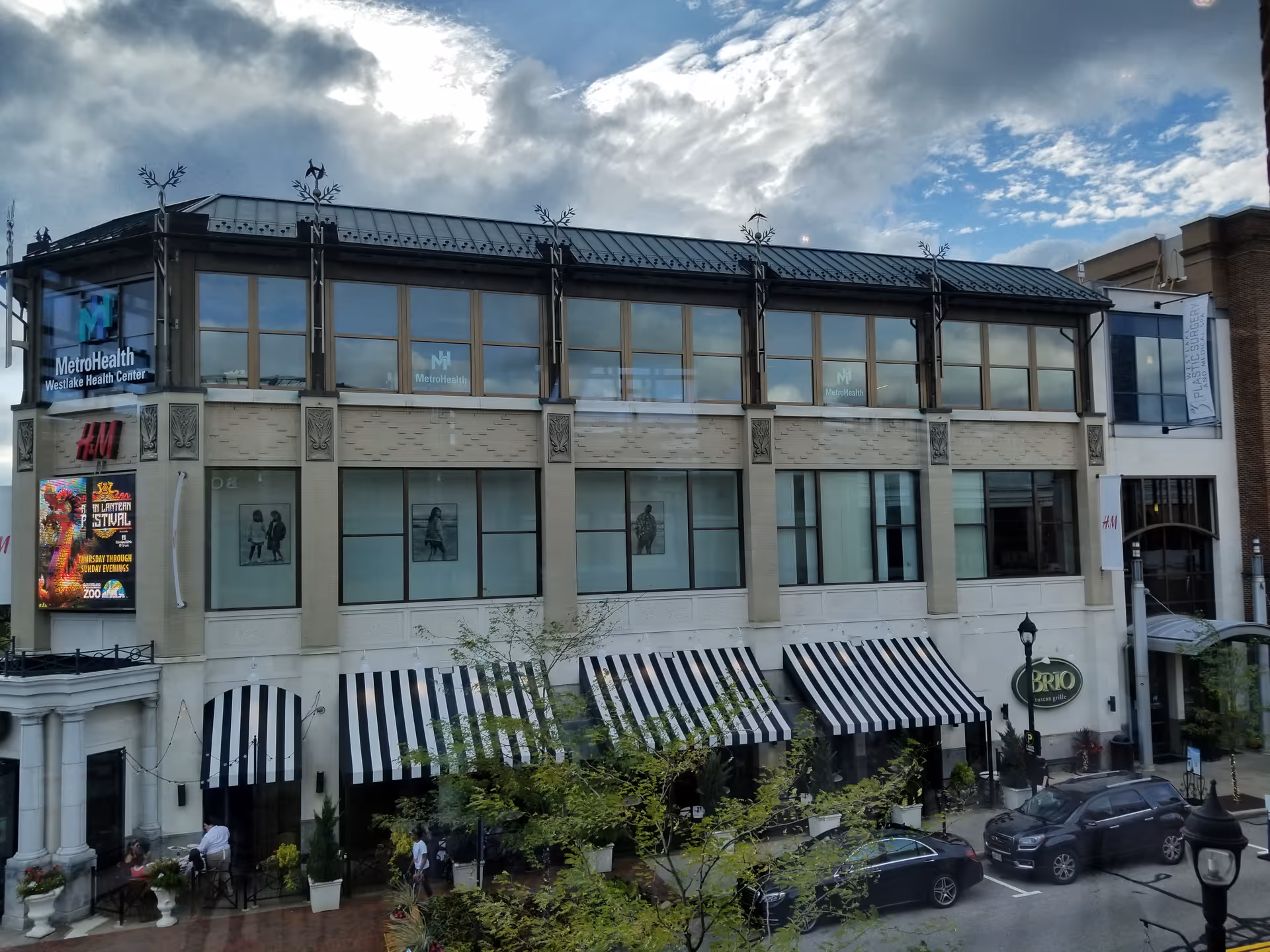 Multi-story storefront building with striped awnings, street view, and MetroHealth Westlake Health Center signage.