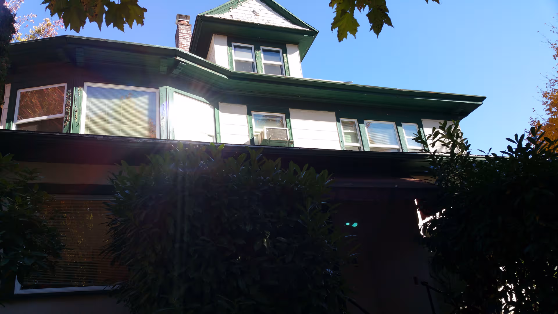 Two-story building with green trim and shrubs in front.