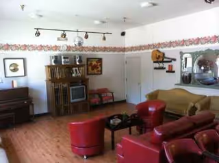 Cozy living room in Lakeview Lodge with red chairs, sofa, piano, and decorative wall border.