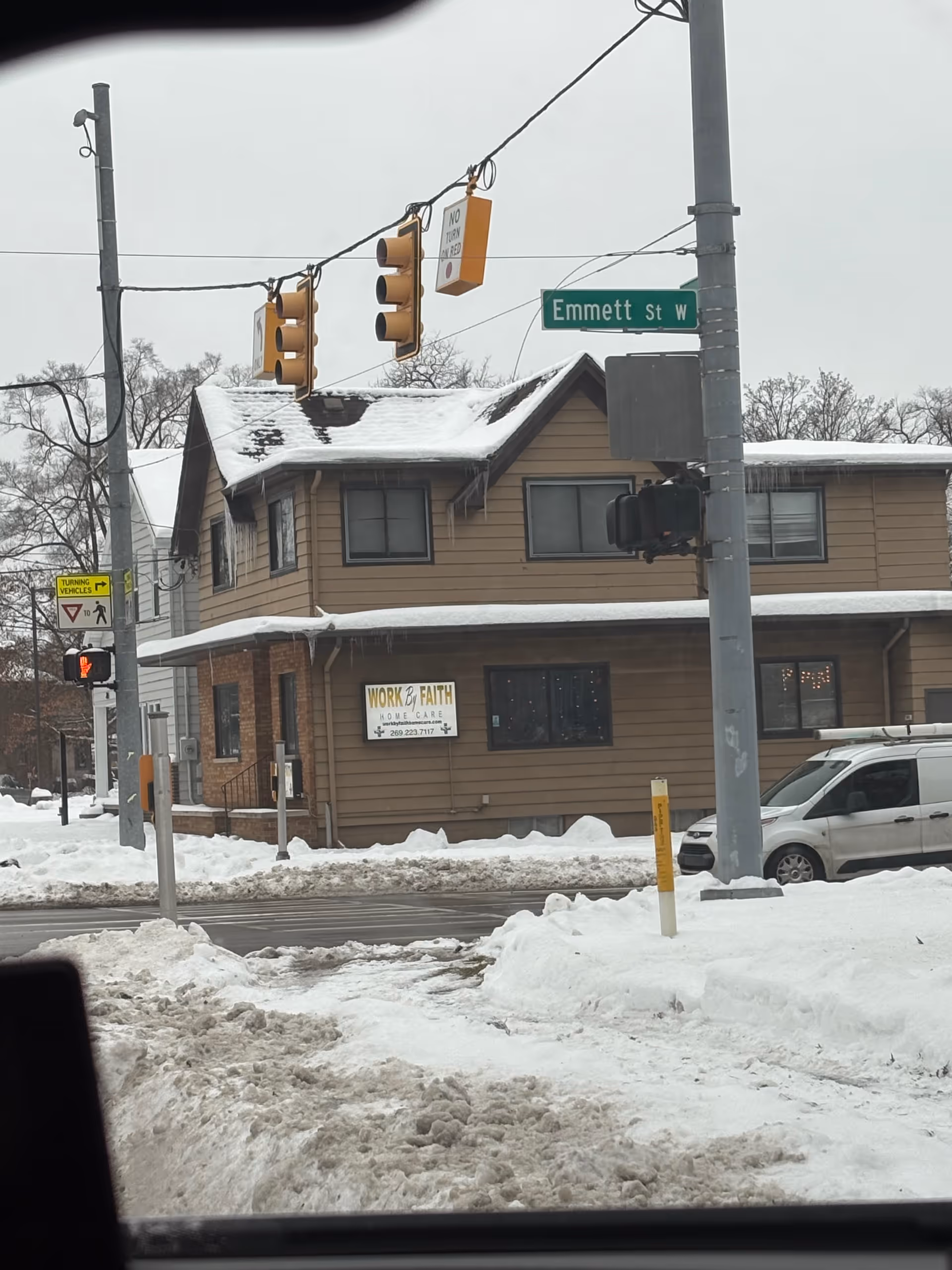 Snowy street view of a brown, two-story building labeled Work & Faith Home Care.