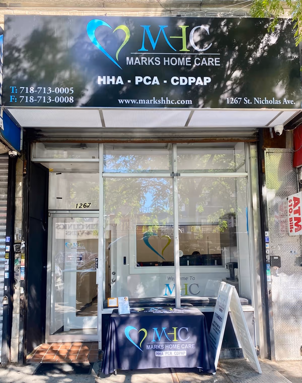 Exterior storefront of Marks Home Care Agency with a logo-bearing table outside.