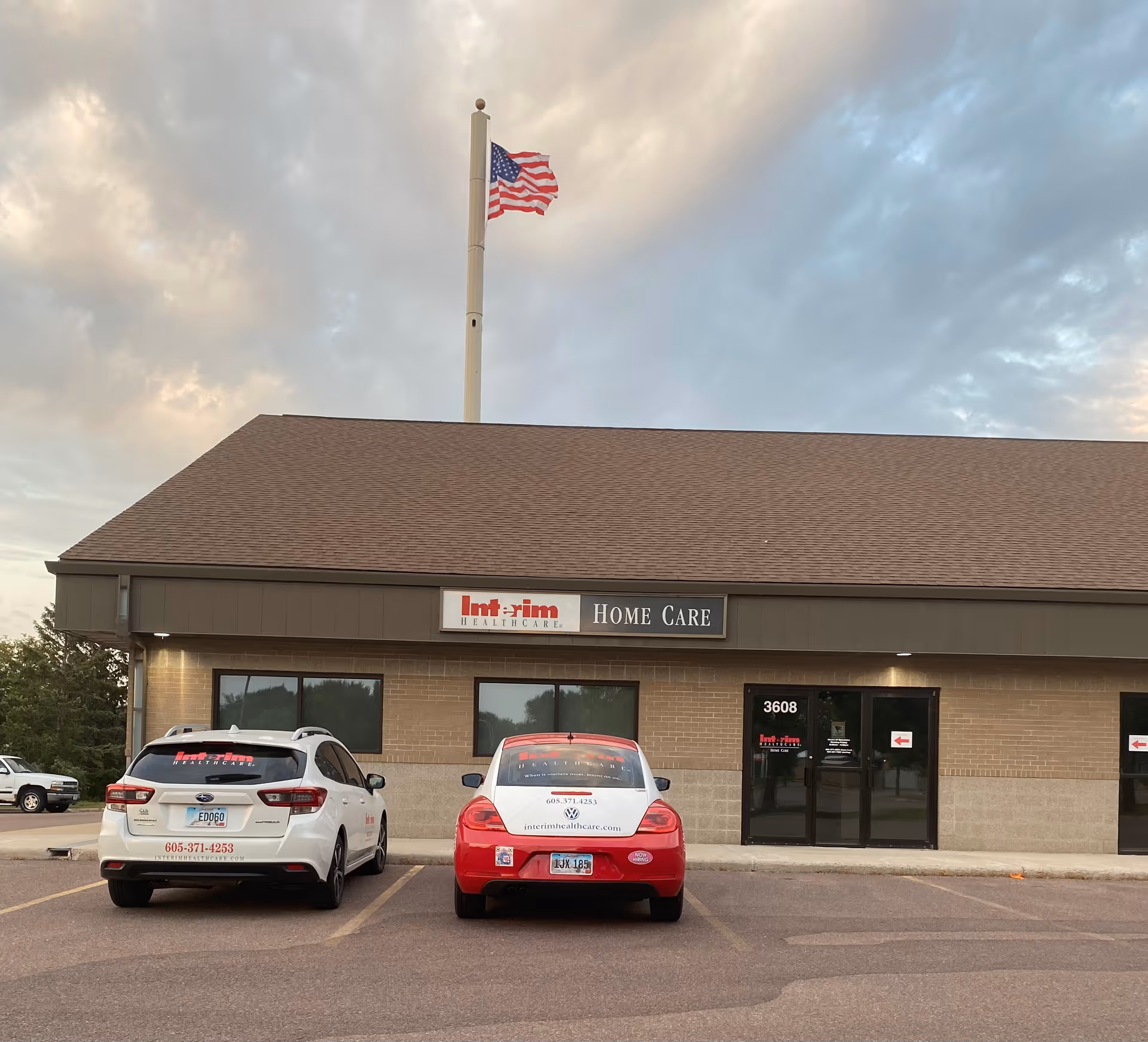 Exterior view of Interim HealthCare Home Care building with parked cars and flagpole.