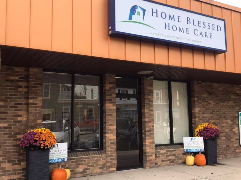 Brick storefront with a Home Blessed Home Care sign and orange mums.