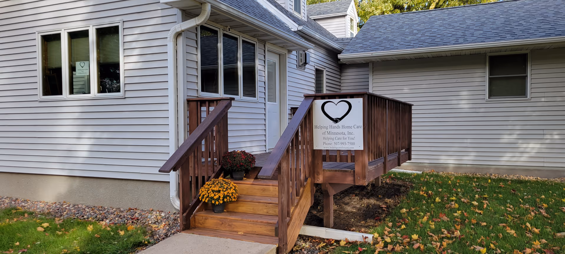 Exterior view of a gray house with a wooden ramp and Helping Hands sign.