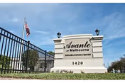 Exterior view of Avante at Melbourne sign with fence, flag, and blue sky.