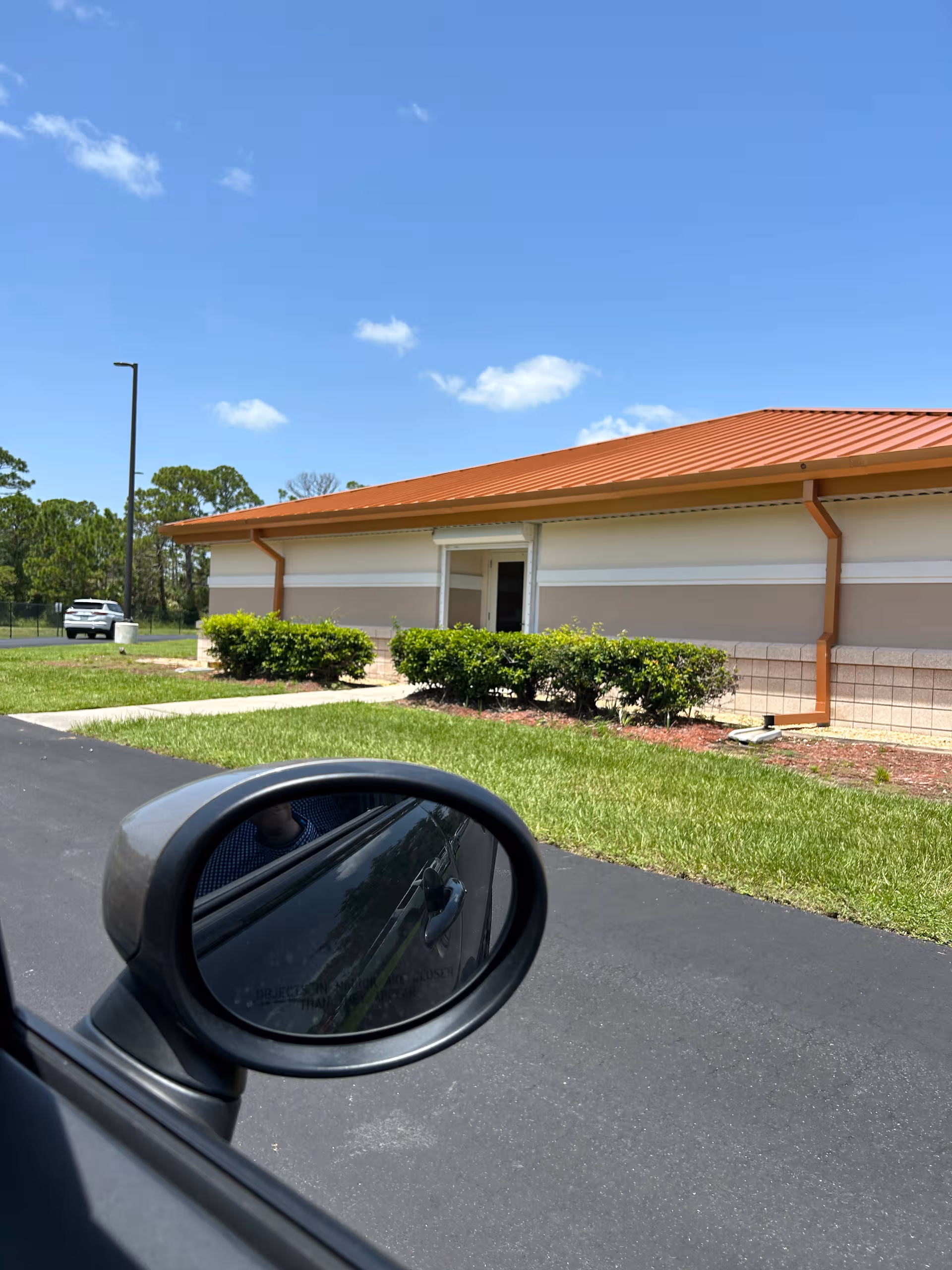Exterior view of a single-story facility with manicured bushes and a red-tiled roof.