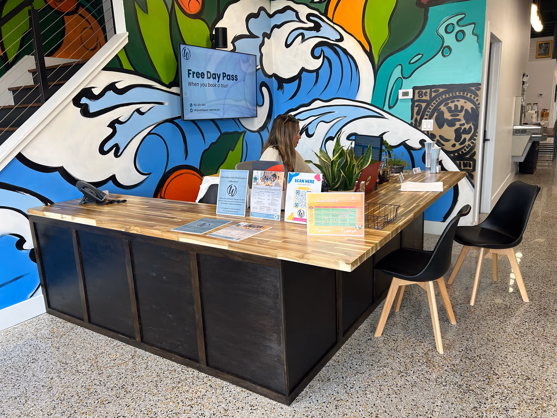 Reception desk with a wooden counter and a colorful mural backdrop.