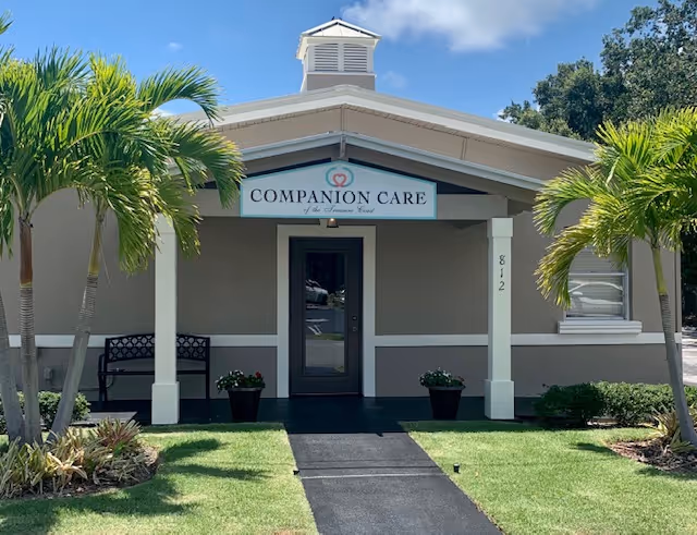 Front exterior of Companion Care facility with palm trees and sign.
