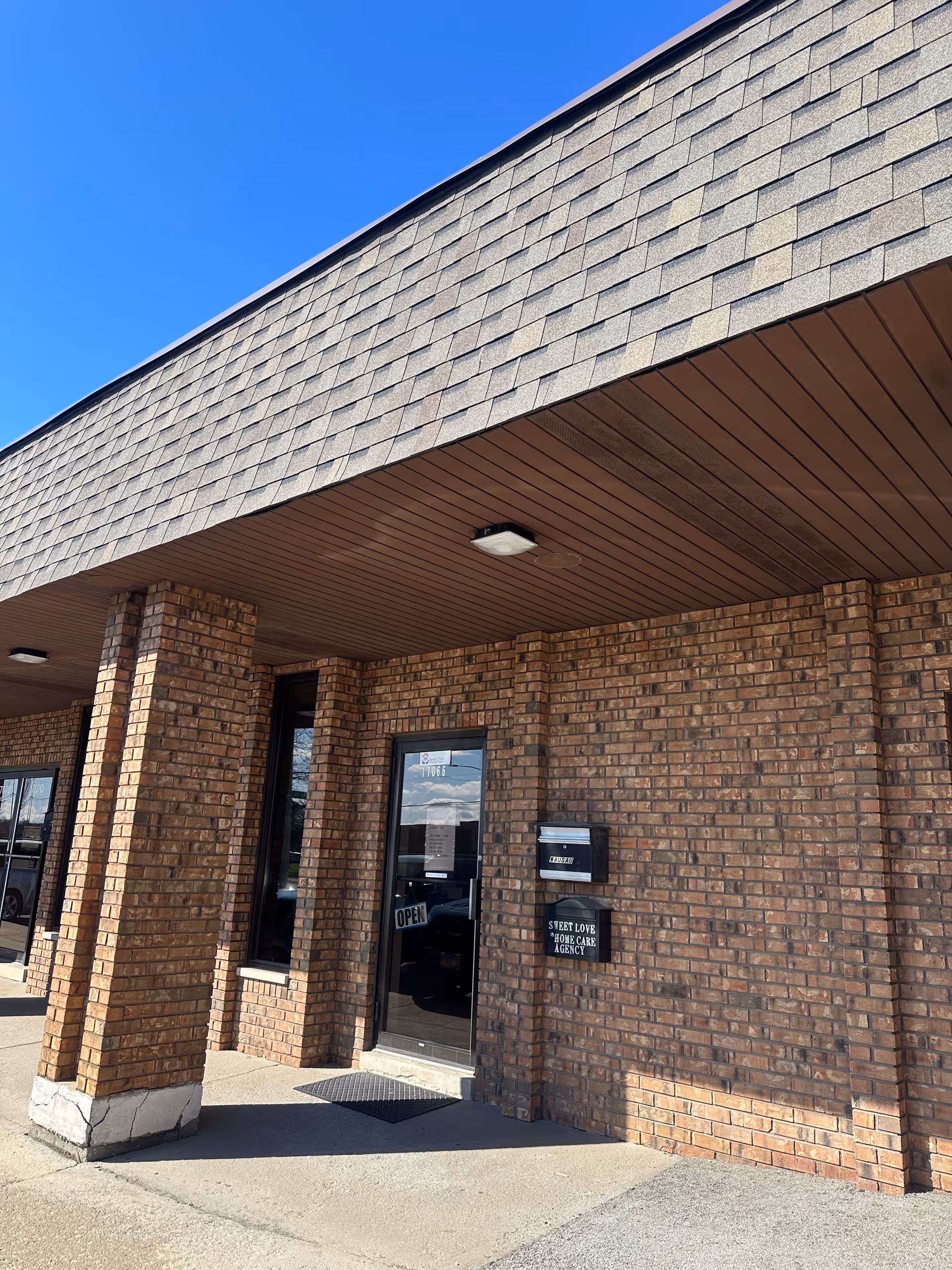 Brick exterior of a care facility with glass door and Sweet Love Home Care Agency sign.