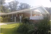 A single-story building with a slanted roof and a landscaped front yard.