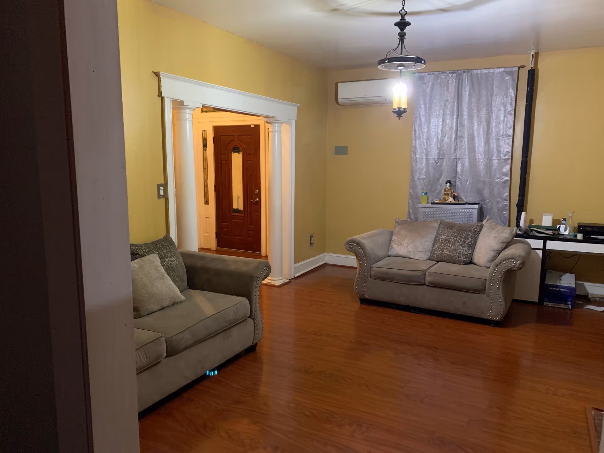 Two beige couches face each other in a yellow-walled living room with wooden floor.