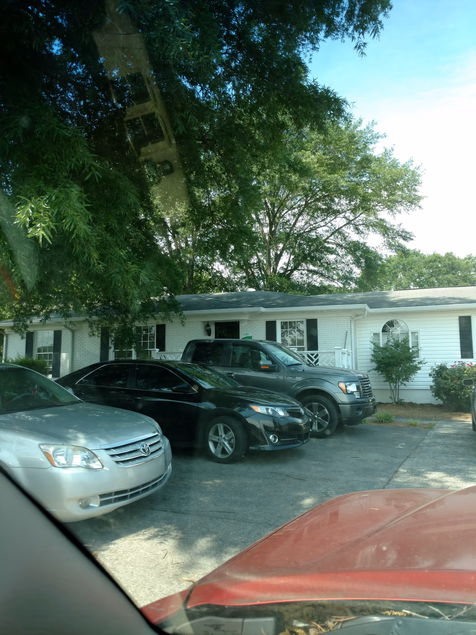 White single-story building with a parking lot and trees in front.