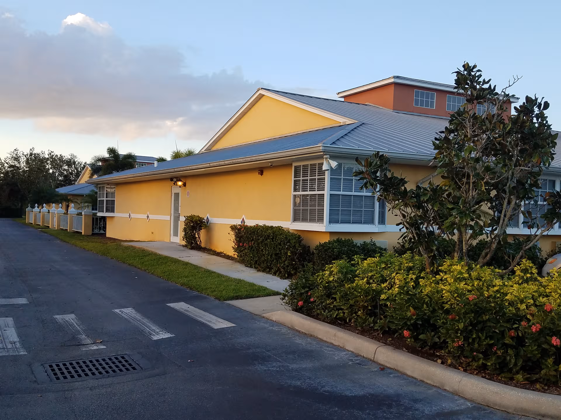 Exterior view of The Vista at Hammock Cove, a yellow senior living facility with shrubs.