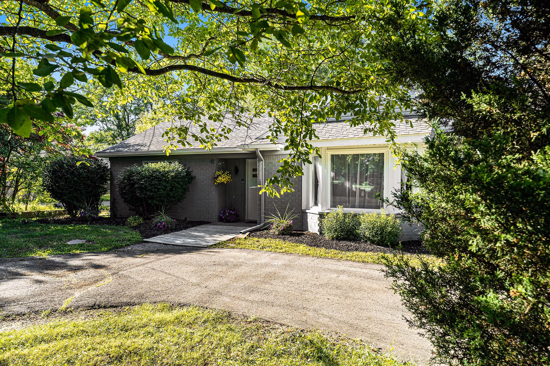 Single-story building entrance with shrubs, walkway, and trees.