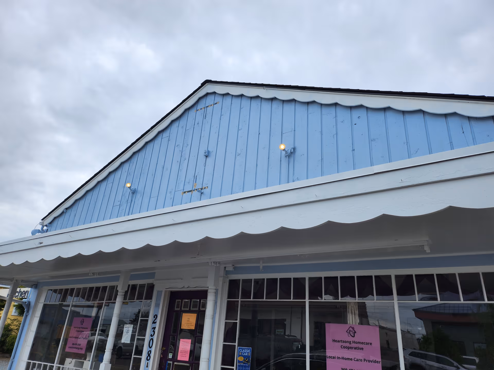 Blue storefront with scalloped white awning and large glass windows