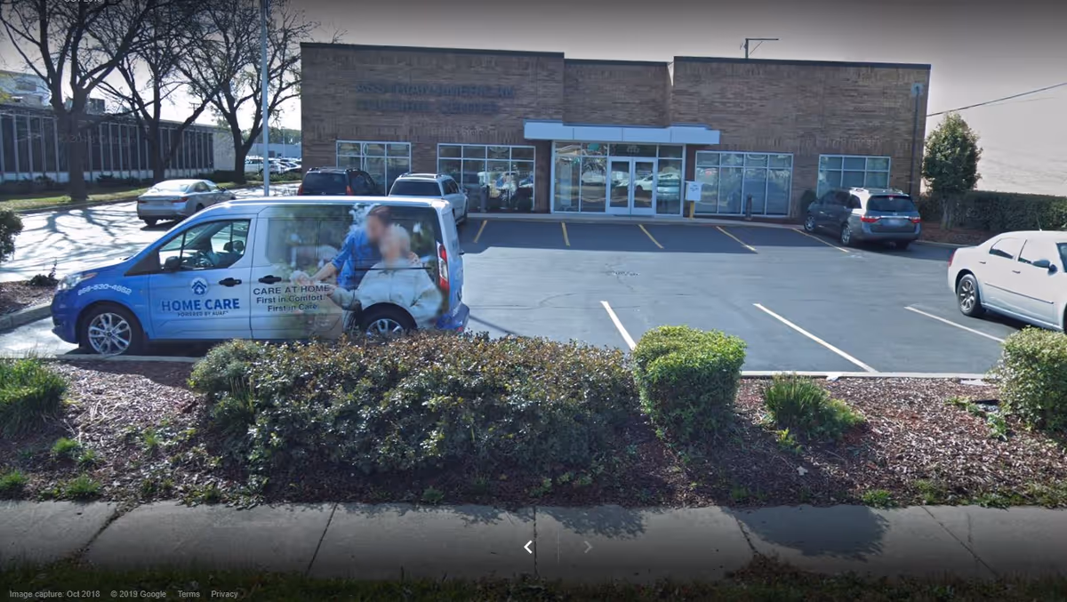 Blue Home Care van parked outside a brick facility with glass doors.